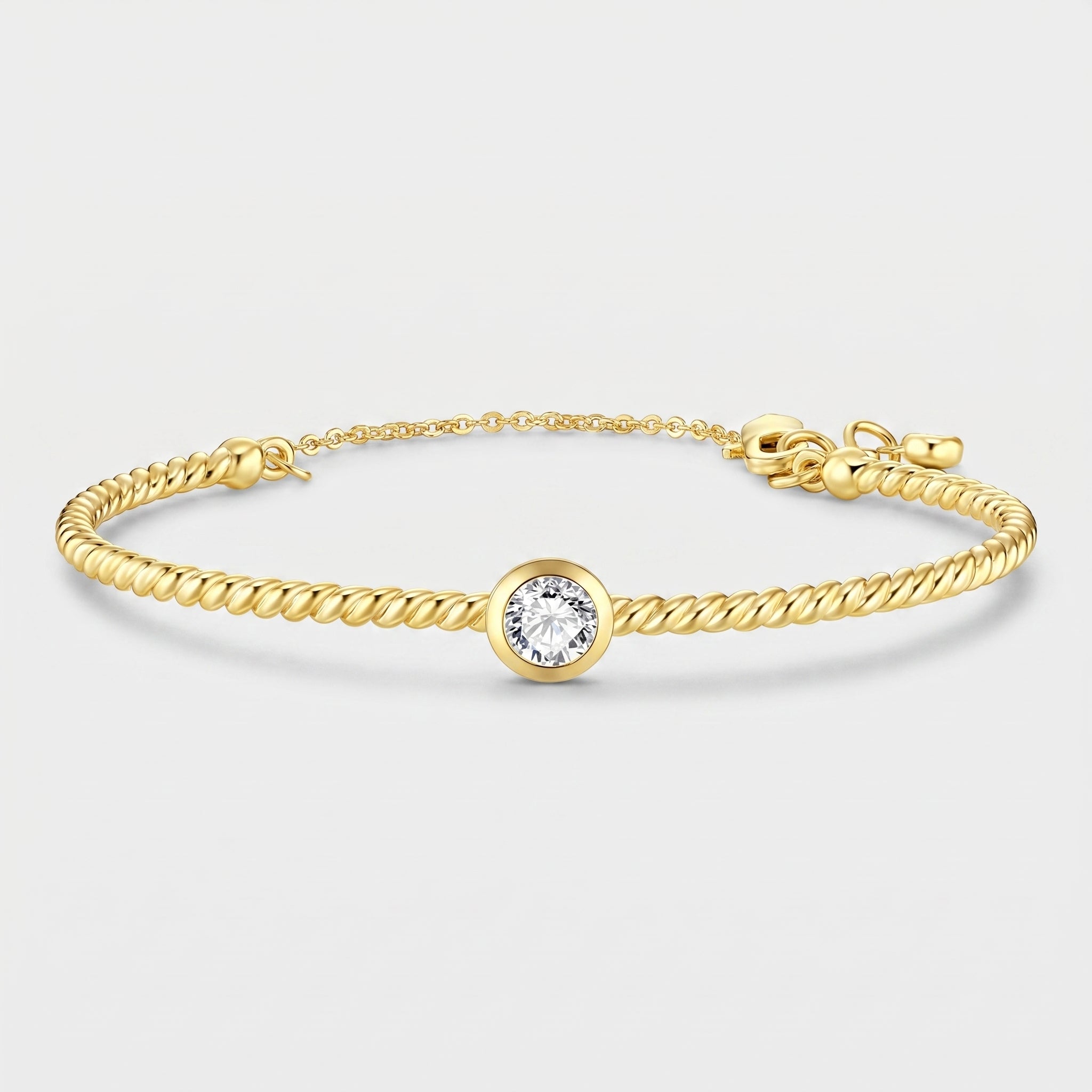 A gold rope bracelet with a central bezel-set round clear gemstone, displayed on a light gray background.