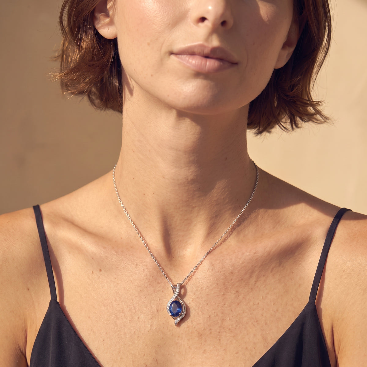 Blue sapphire pendant necklace worn close-up, showing sterling silver setting