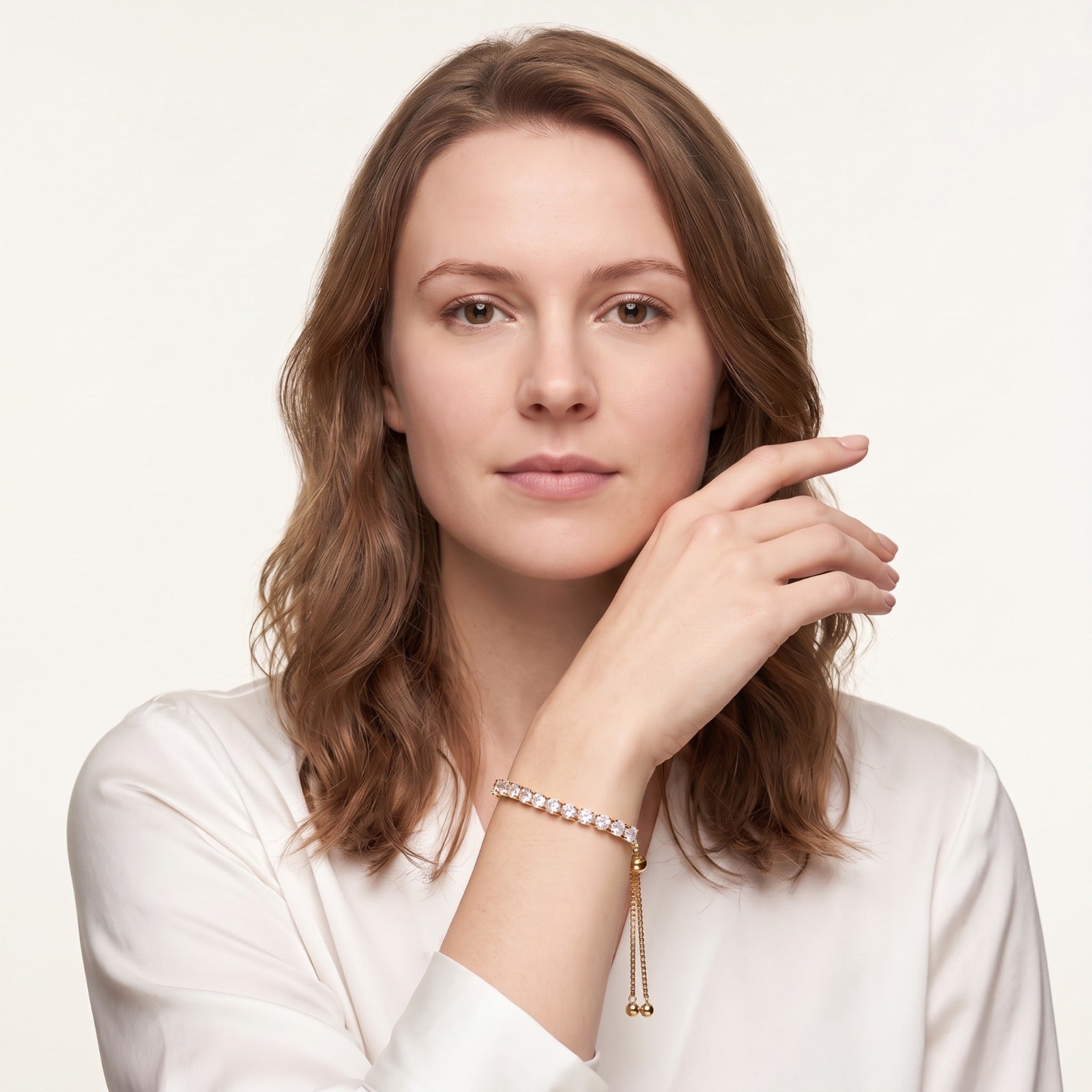 Woman wearing the 14K gold plated adjustable CZ tennis bracelet with her hand raised to her face