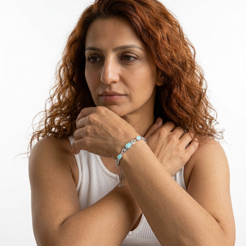 Close-up of a woman wearing the opal bracelet on both wrists, arms crossed.