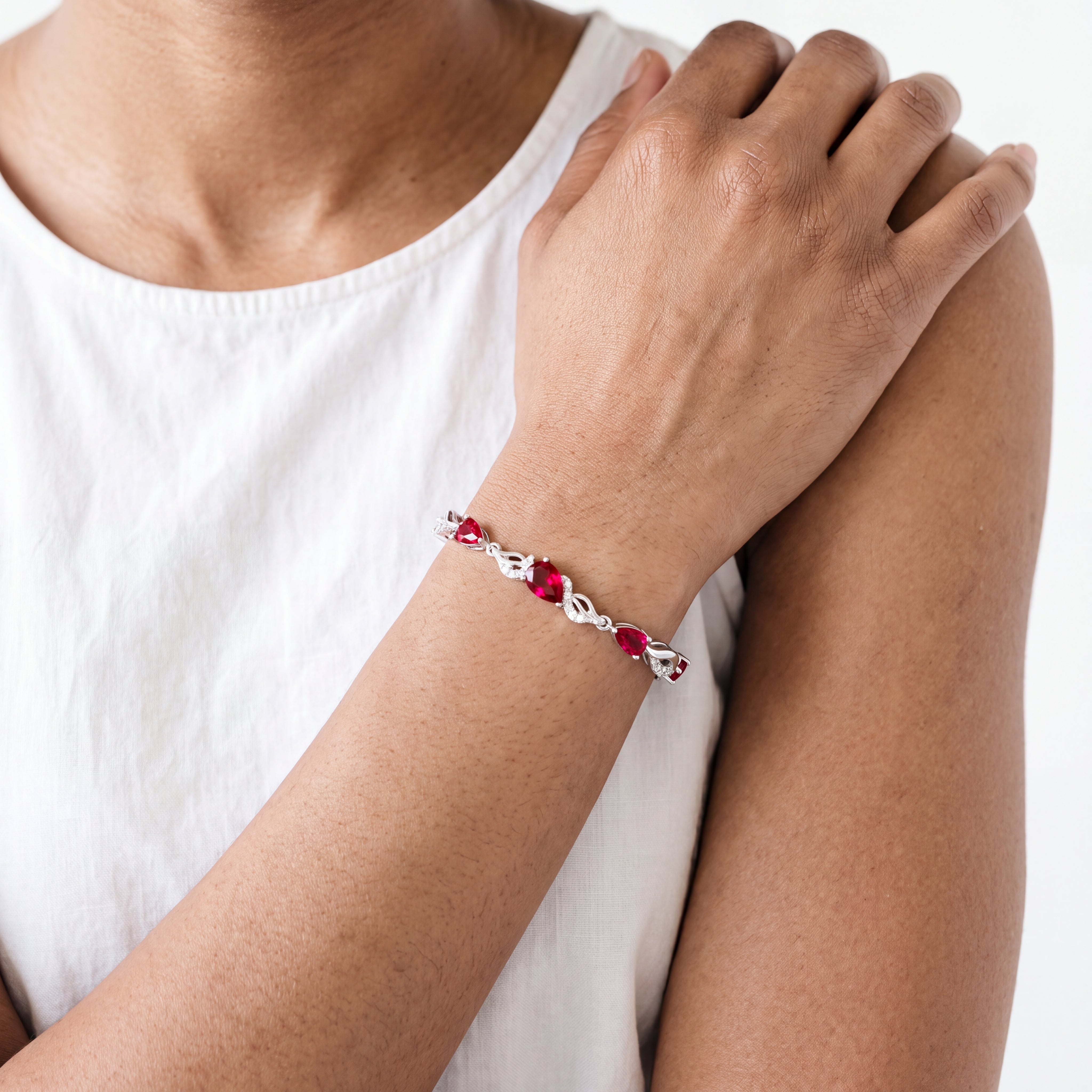 Close-up of a woman wearing the ruby bracelet with arms crossed, showing the full sparkle of the stones.