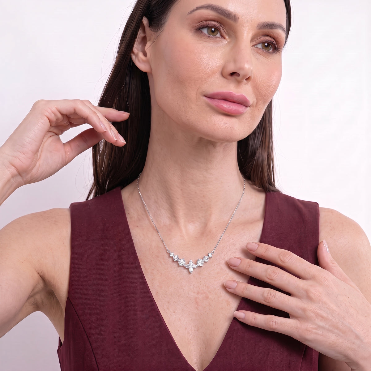 Woman touching her collarbone while wearing a sparkling silver seven stone necklace