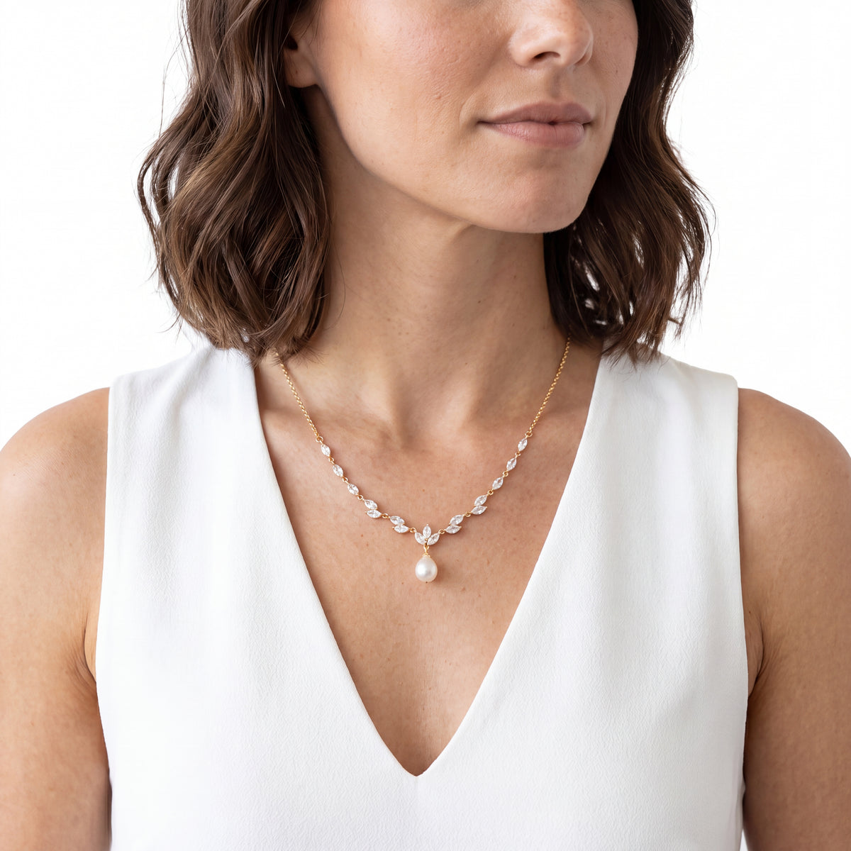 Close-up of a marquise cubic zirconia vine necklace with a pearl drop on a white dress