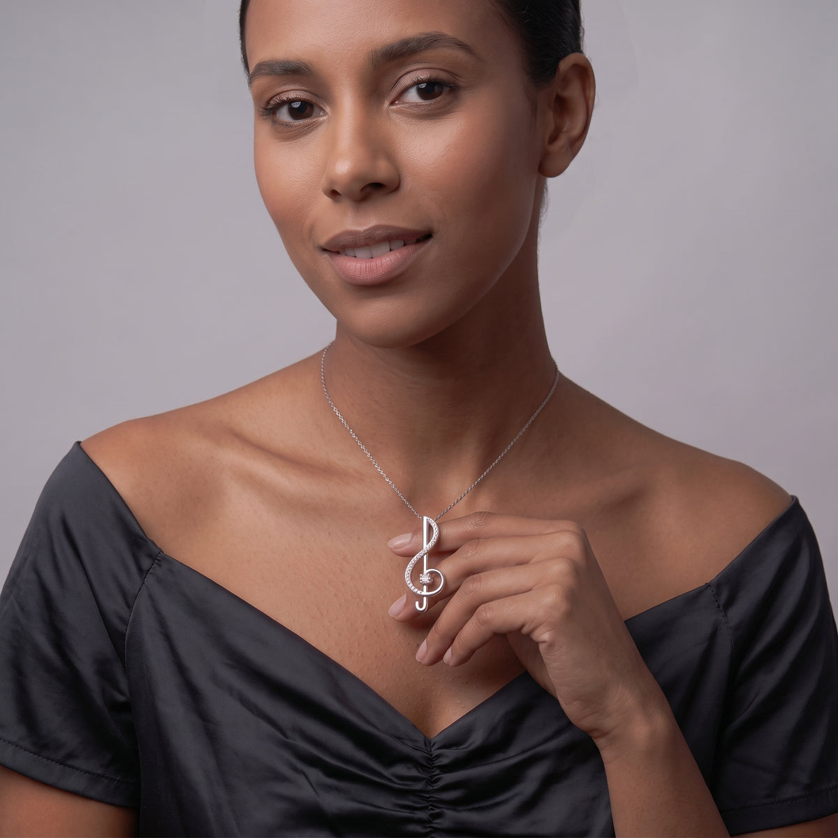 Woman in a black dress wearing a treble clef moissanite pendant necklace