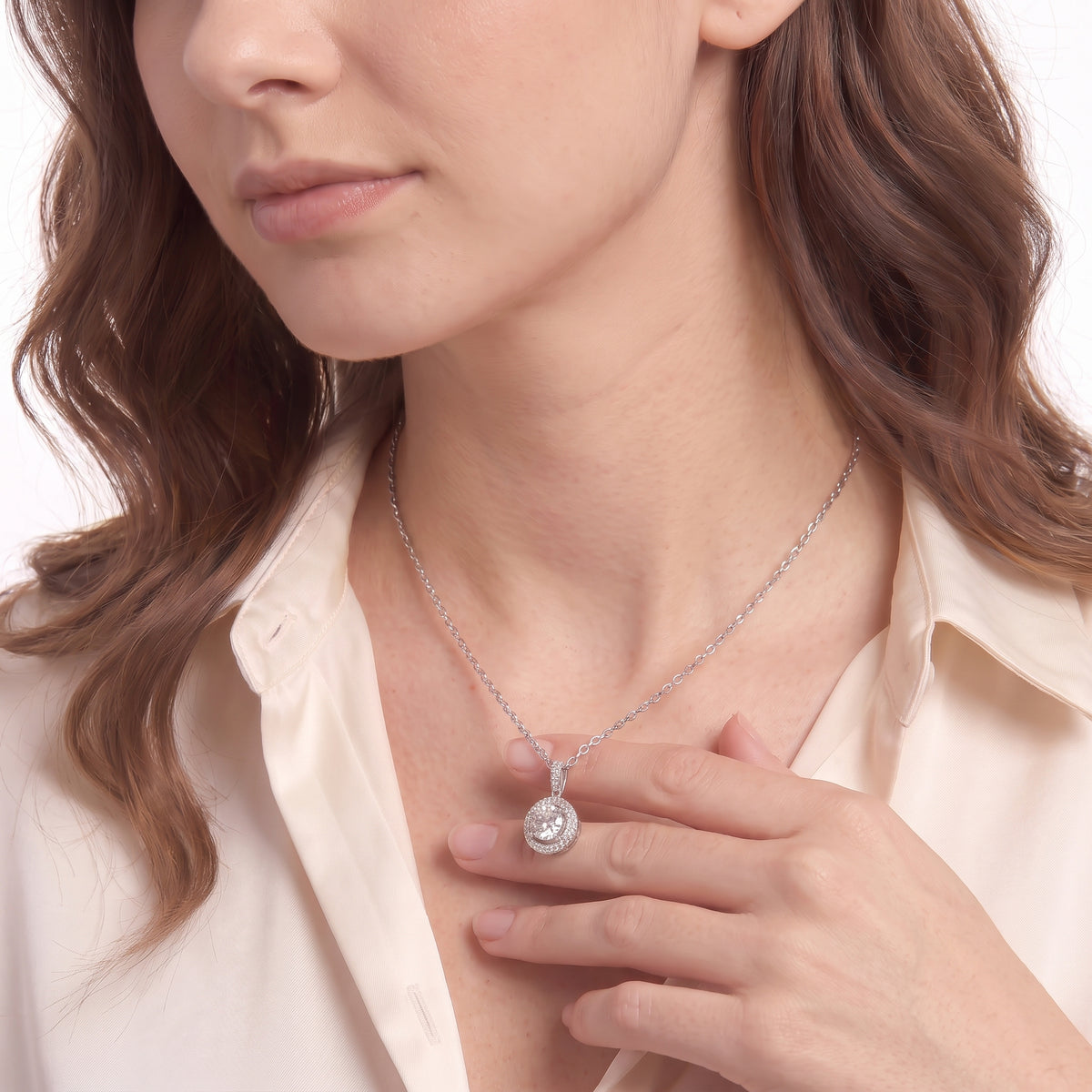 Woman touching a round moissanite halo pendant necklace on a thin silver chain