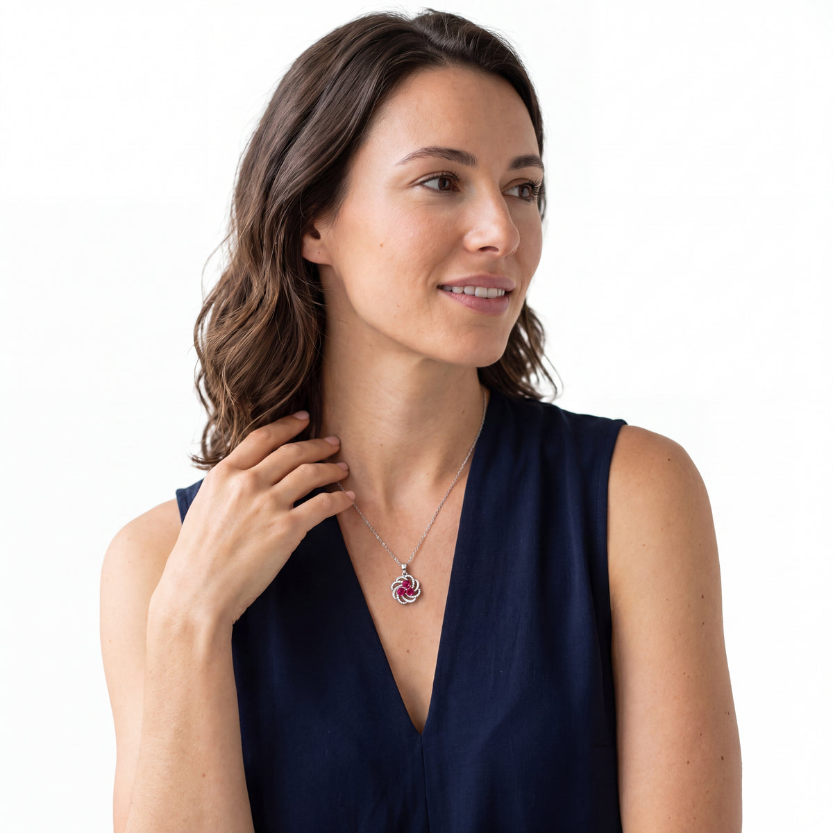 Woman in a navy top wearing a red ruby three stone pendant necklace