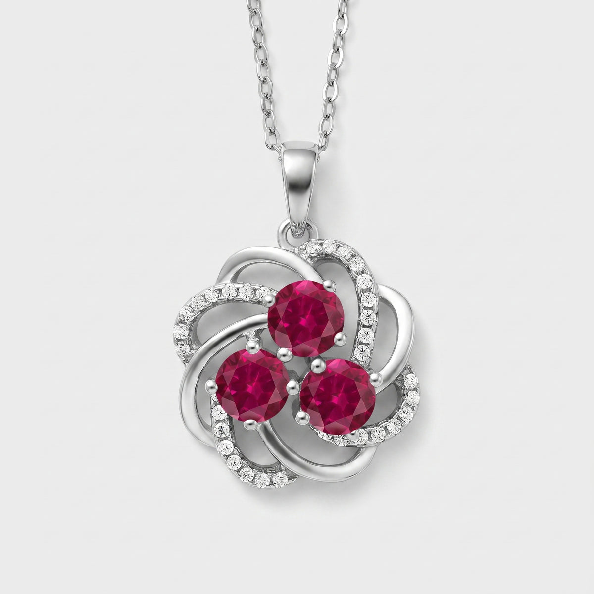 Sterling silver swirl pendant with three round lab created rubies and white CZ accents