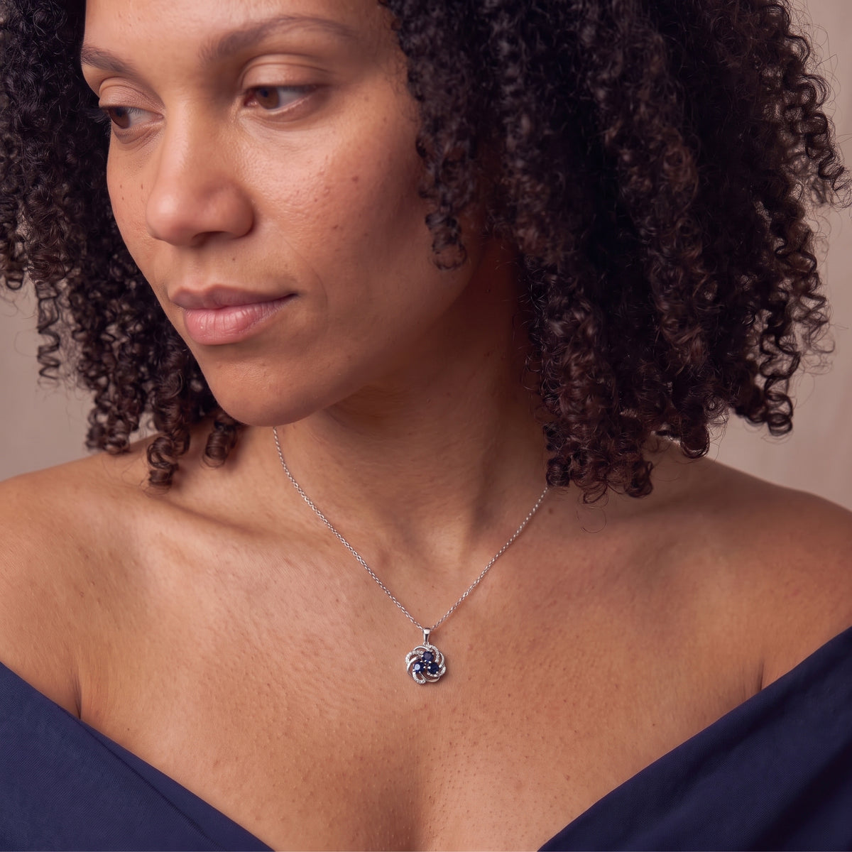Close-up of a blue sapphire and silver blossom necklace worn on bare shoulders