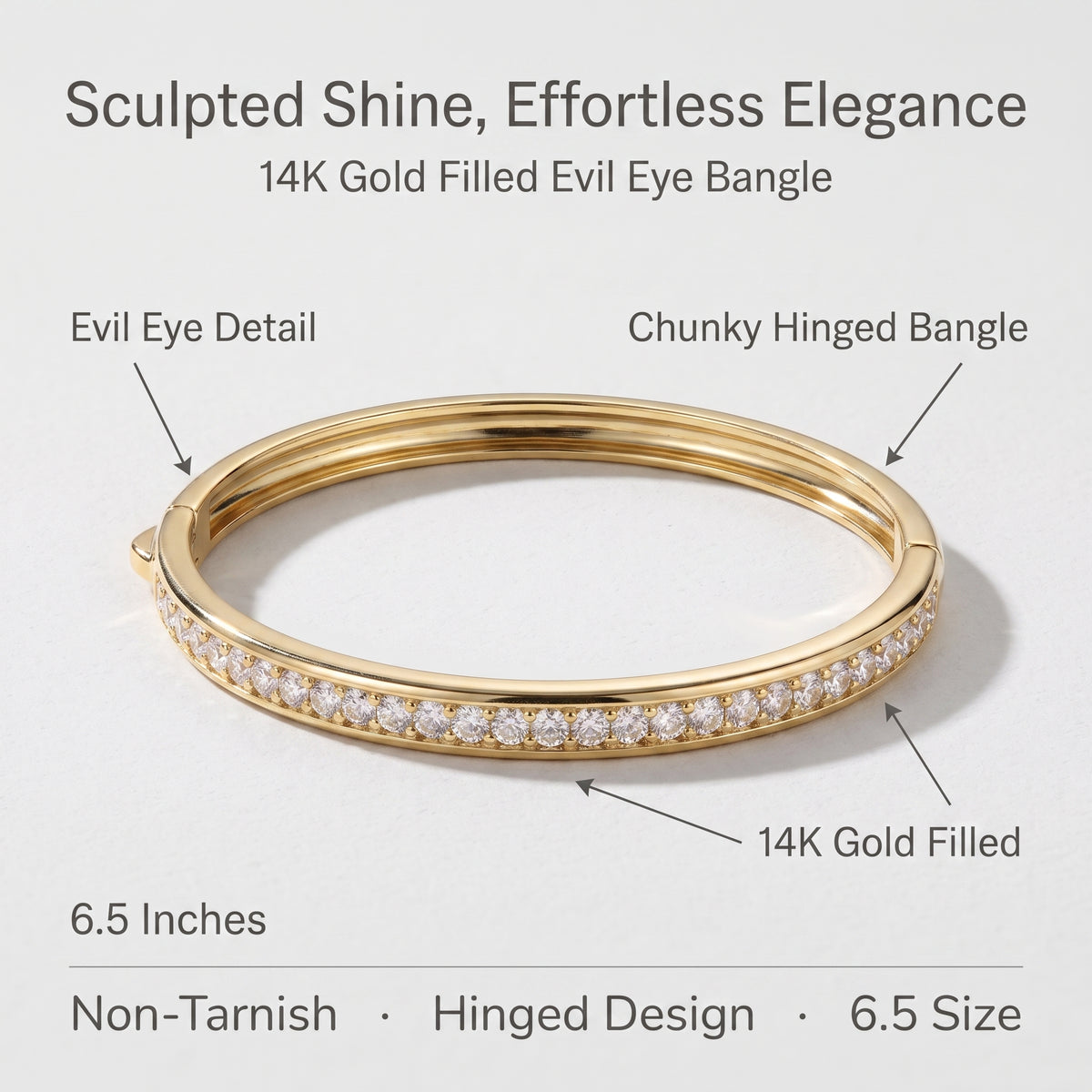 A gold hinged bangle bracelet with a row of clear stones on one side, shown on a light gray background with text callouts reading 'Evil Eye Detail,' 'Chunky Hinged Bangle,' '14K Gold Filled,' and '6.5 Inches.