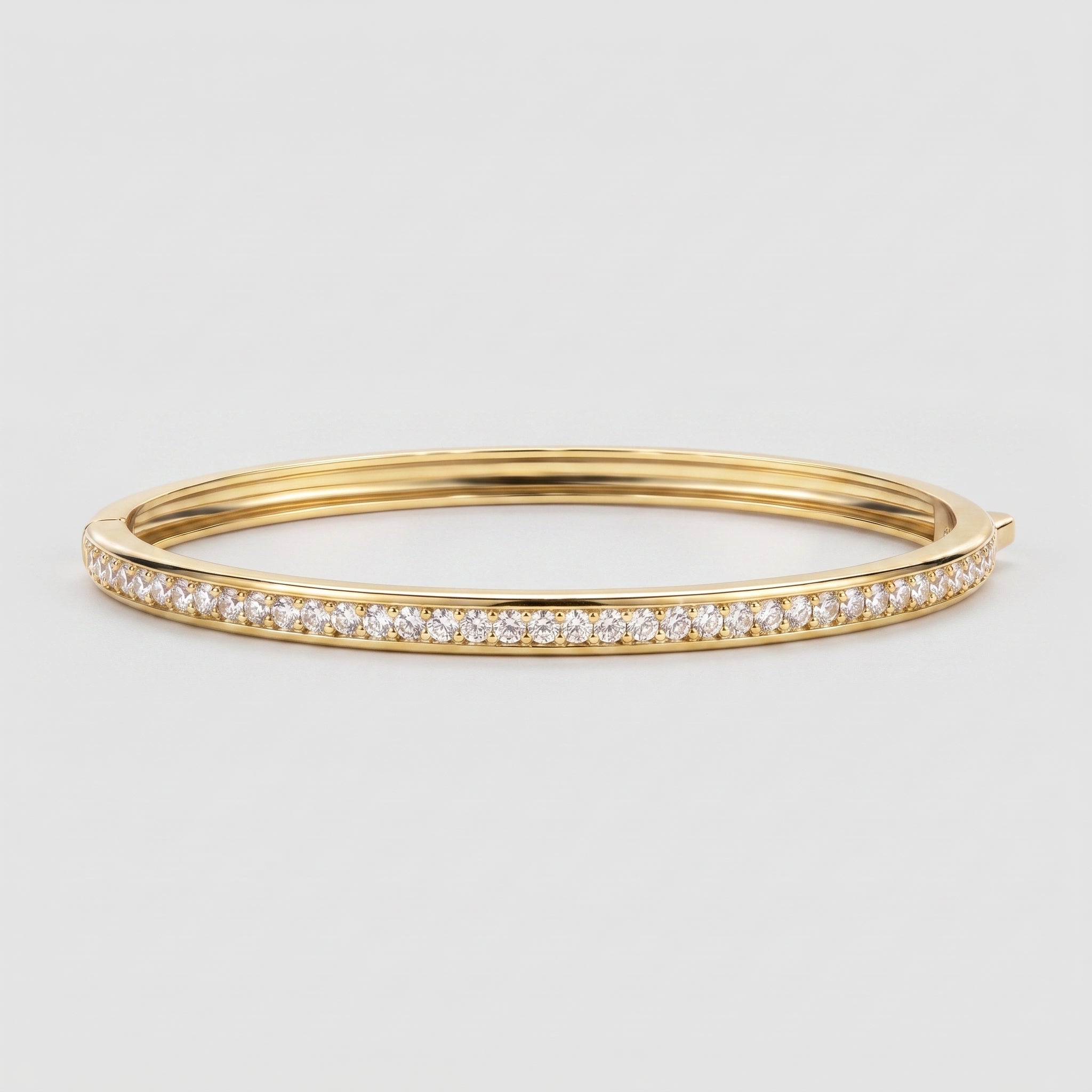 A gold hinged bangle bracelet featuring a single row of pavé-set round diamonds along the front edge, shown against a light gray background.