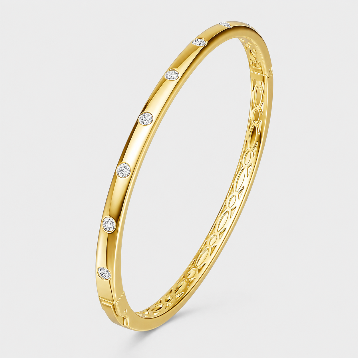 Gold bangle bracelet with round pavé stones and decorative openwork interior on a light gray background