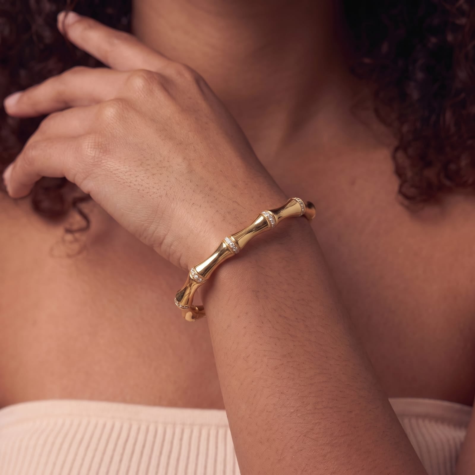 Gold bamboo cuff bracelet with sparkling cubic zirconia bands shown on a woman's wrist