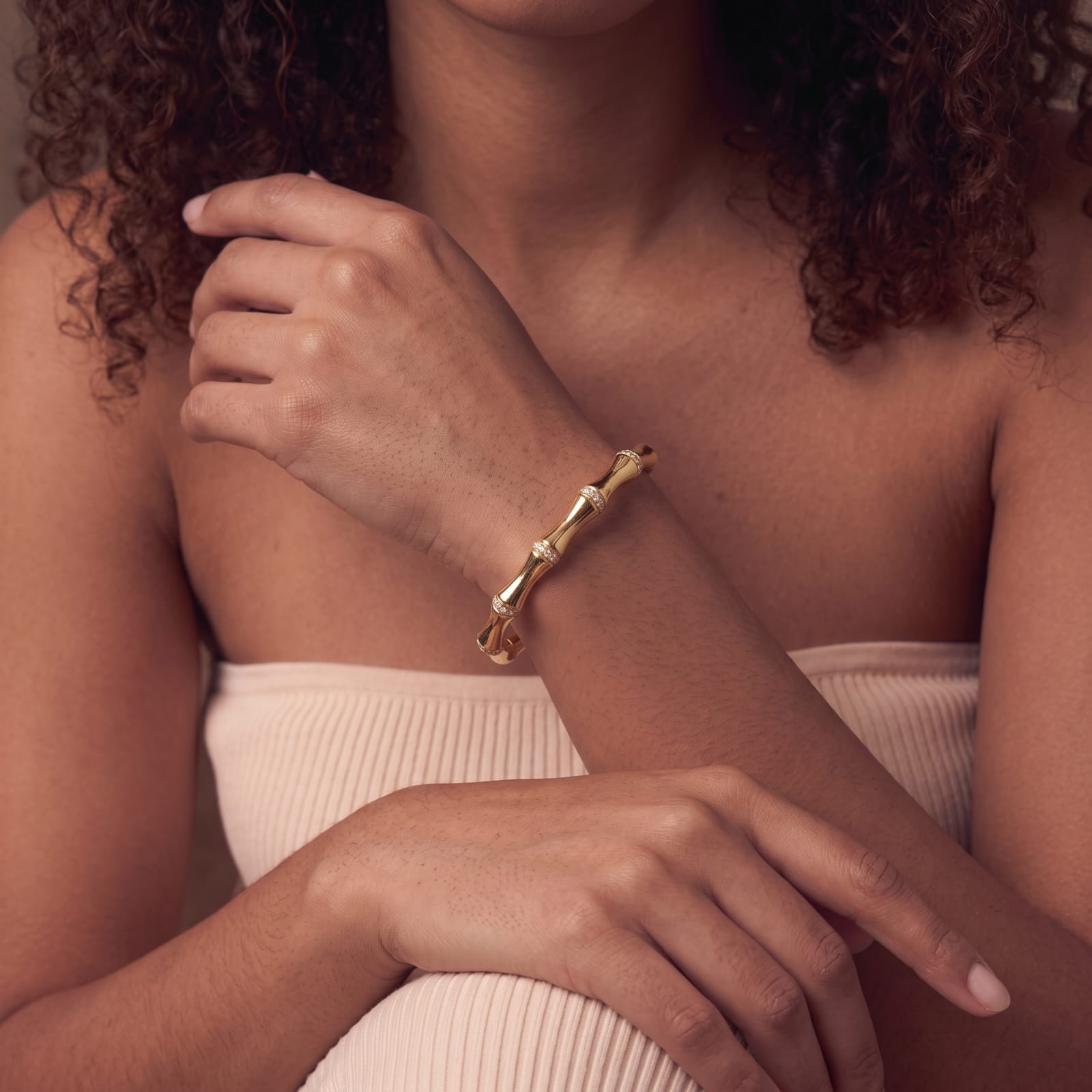 Adjustable open bamboo cuff bracelet in gold worn with a soft cream top