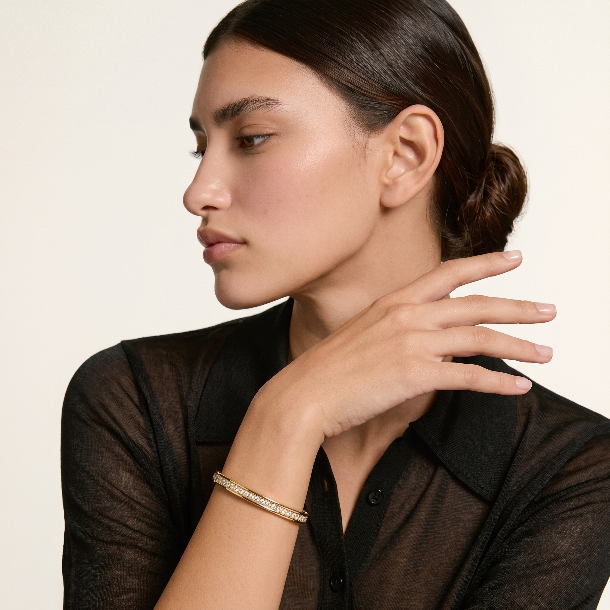 Woman in a black top wearing the gold filled eternity bangle bracelet with her hand near her face