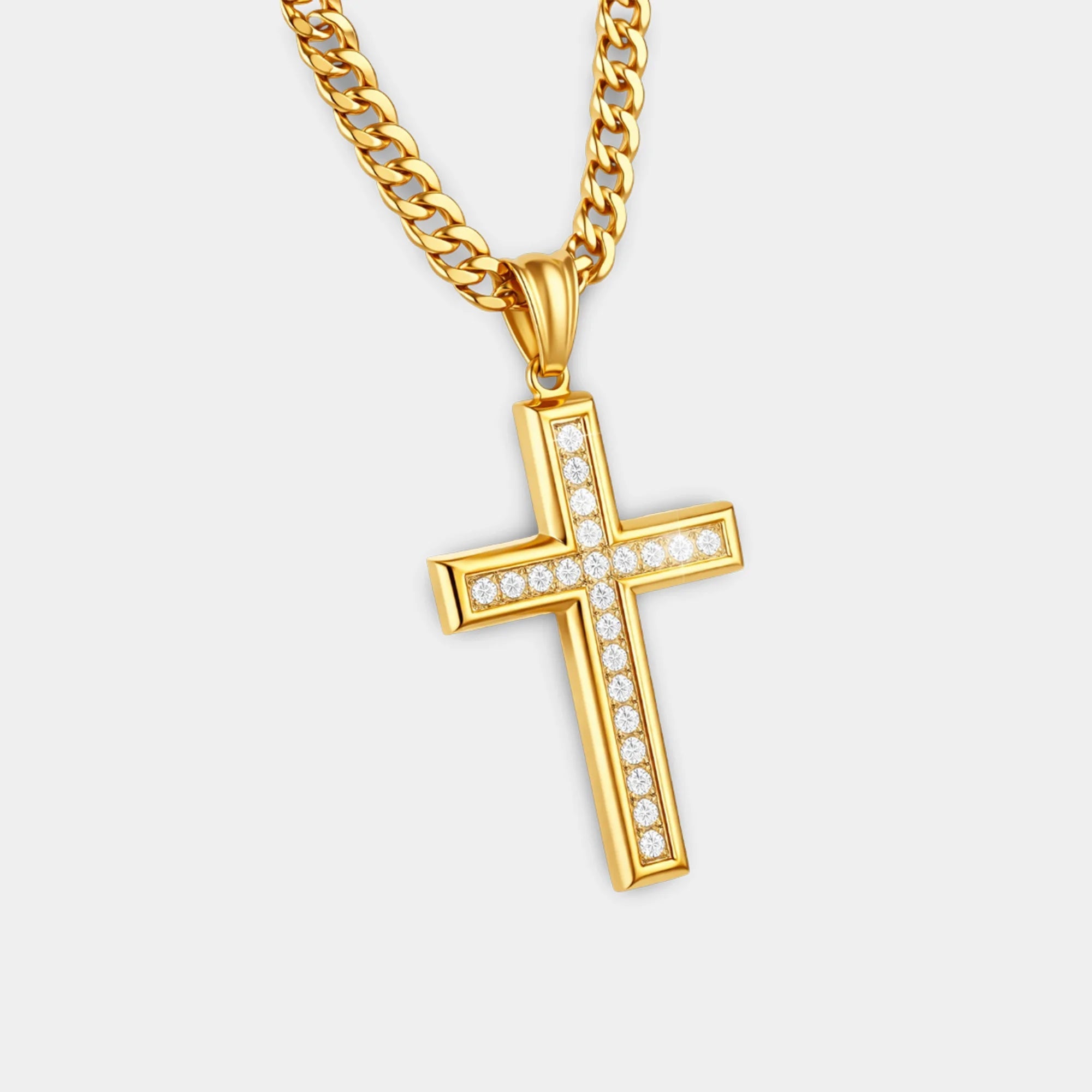 Close-up of the cubic zirconia cross pendant on the gold necklace showing the clear white stones and prong setting