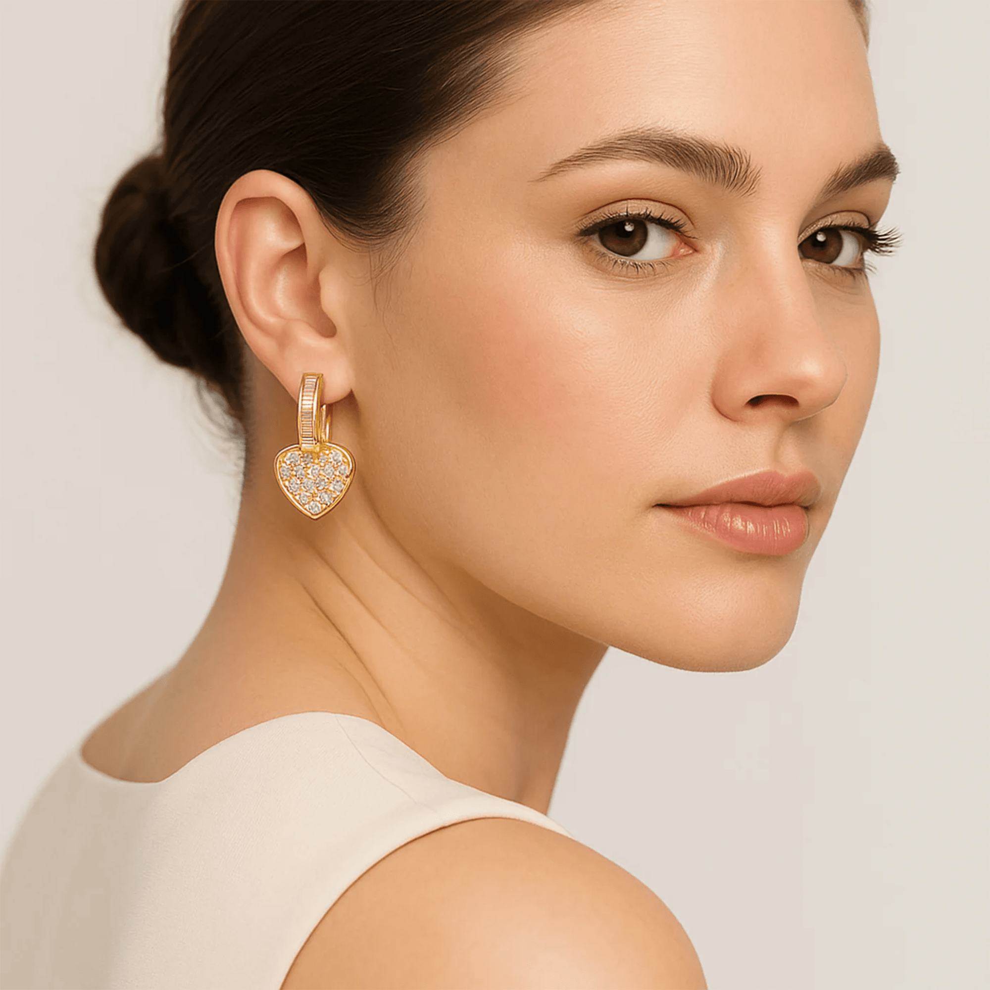 Woman wearing gold heart stud earrings with cubic zirconia.