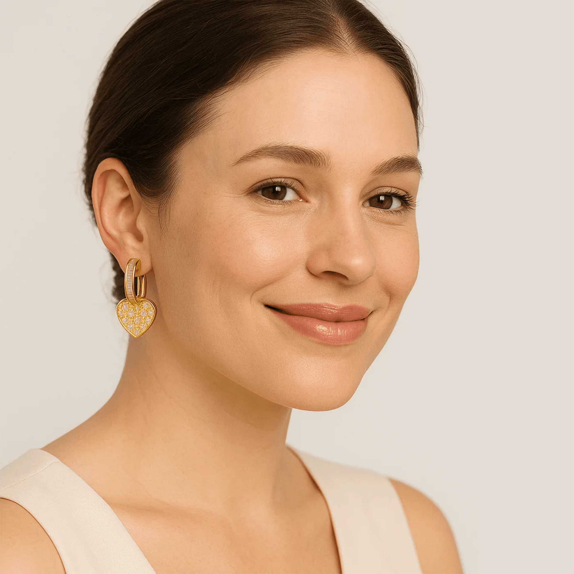 Gold heart stud earrings held up to show the heart shape and shine.