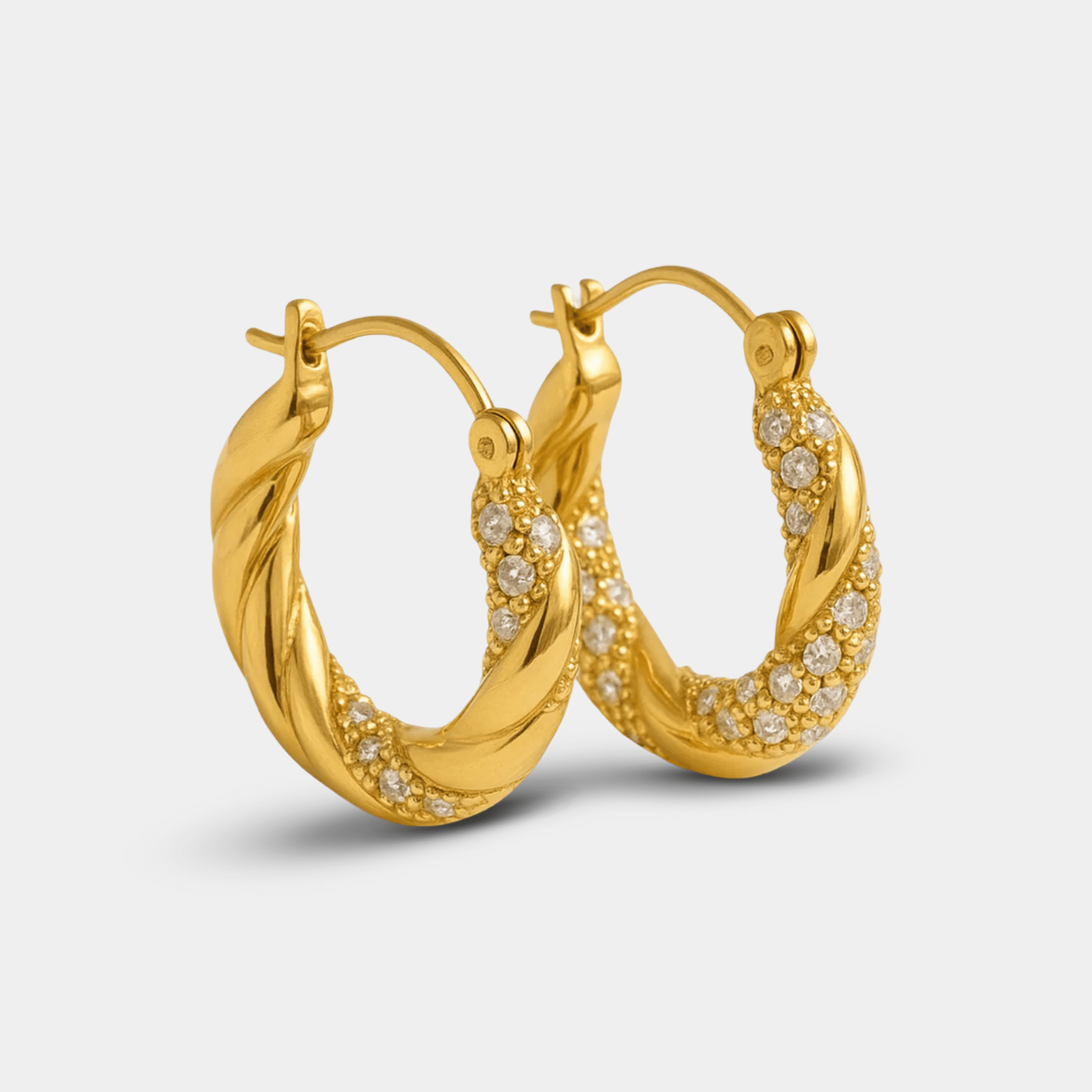 Angled view of twisted gold donut hoop earrings with pavé zircon detail and hinged snap closure