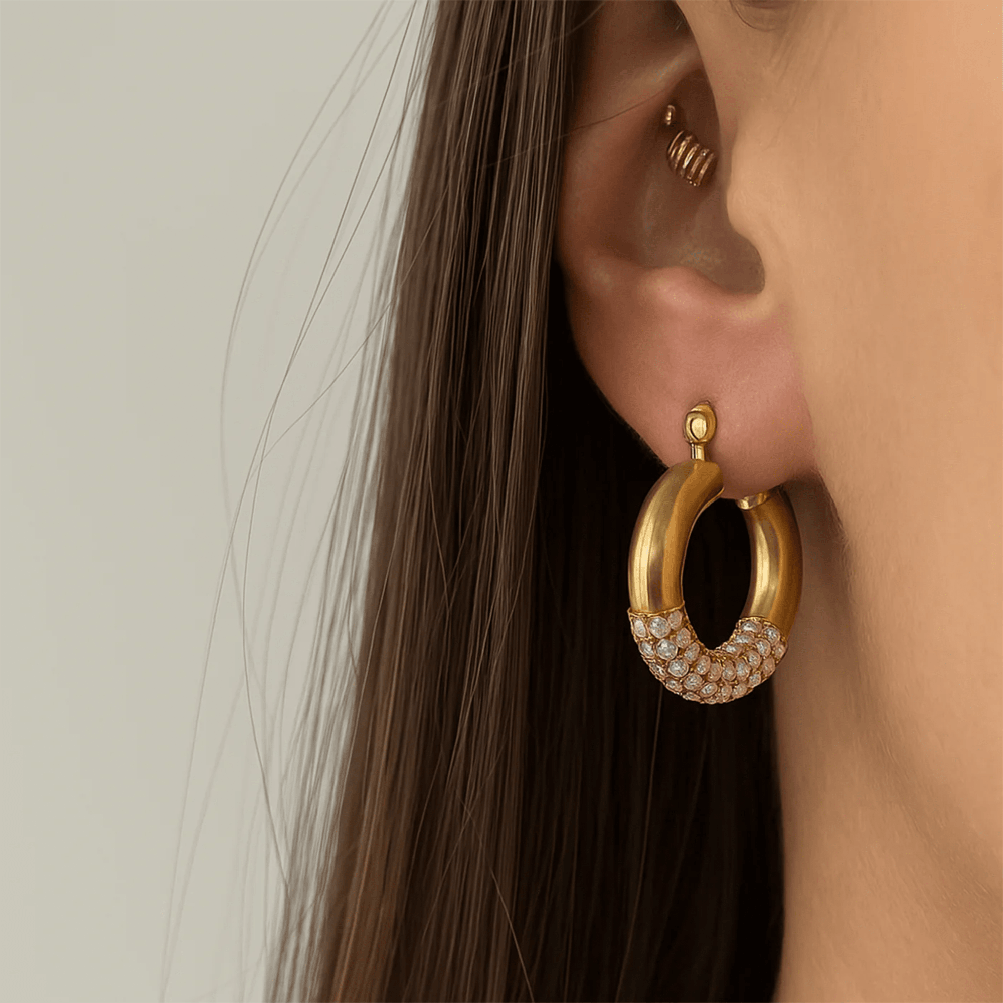 Model wearing a Lustre Luxe gold rhinestone hoop earring, lifestyle close-up on the ear
