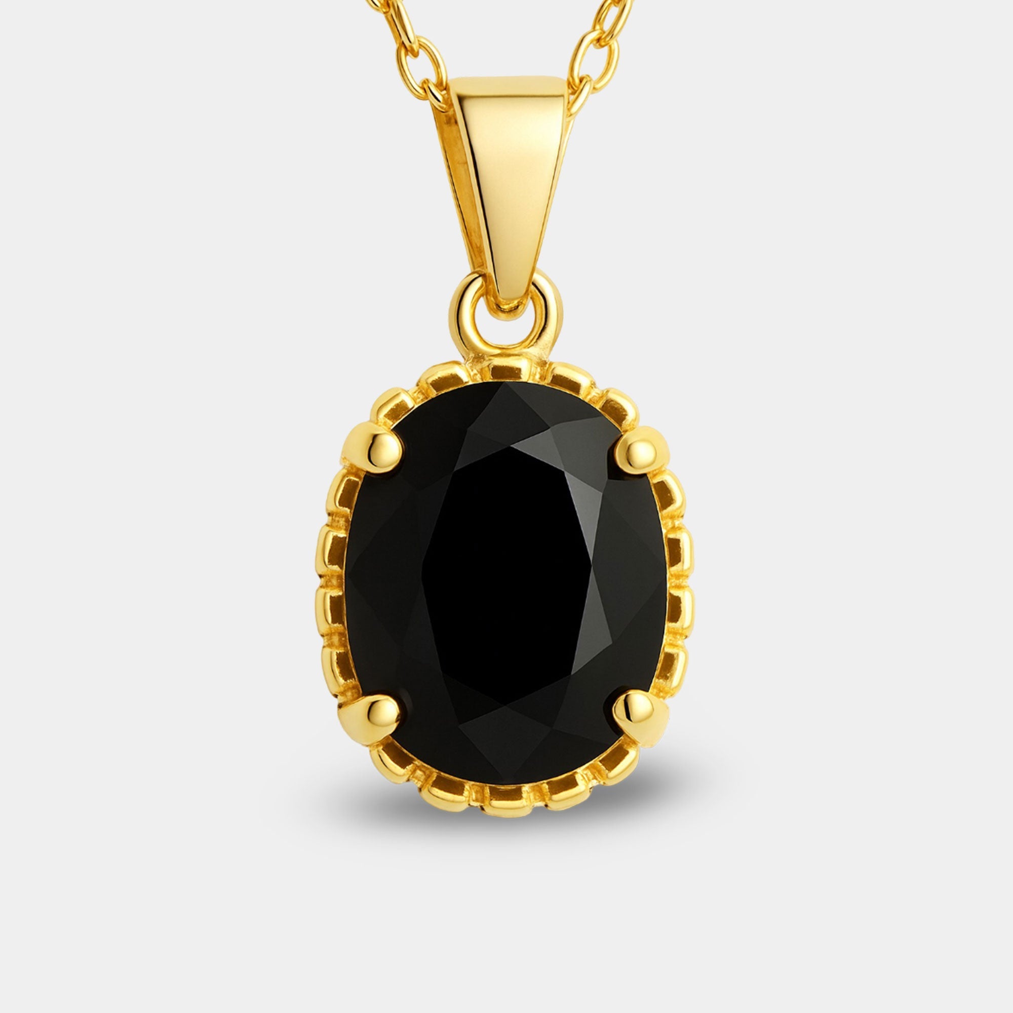 Oval black onyx solitaire pendant shown at an angle on a gold-plated chain.