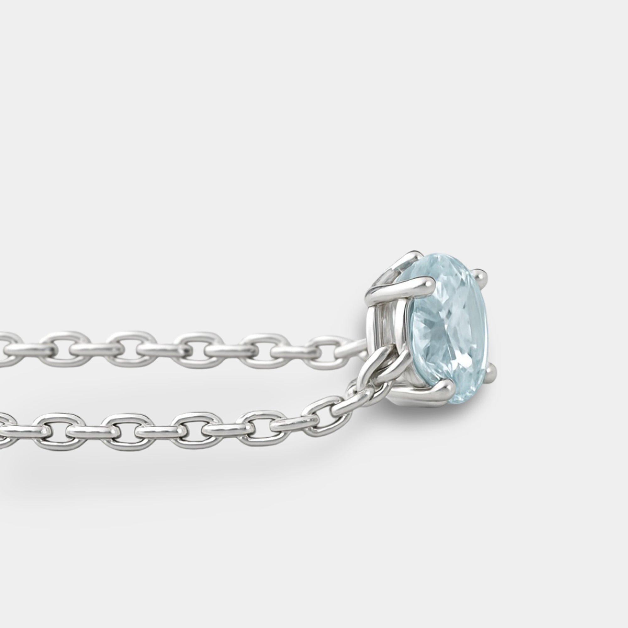 Angled view of the aquamarine solitaire on the thin sterling silver cable chain of the bolo bracelet