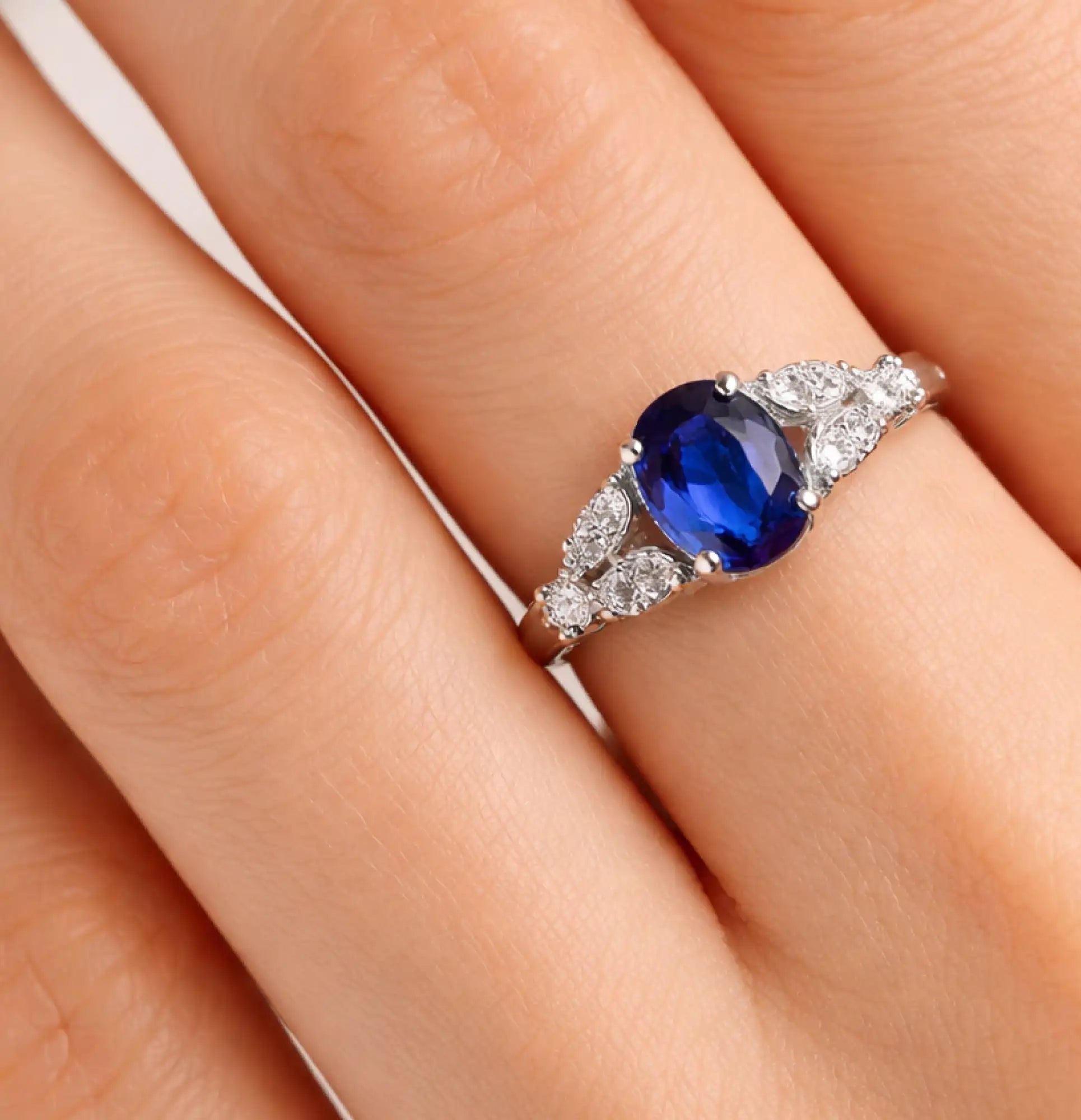 MH Elegance oval blue sapphire stainless steel engagement ring on a neutral background