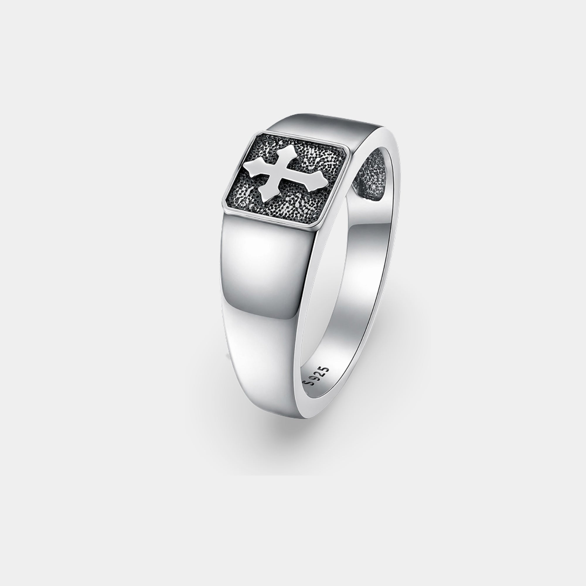 Polished sterling silver cross signet ring for men on a flat surface