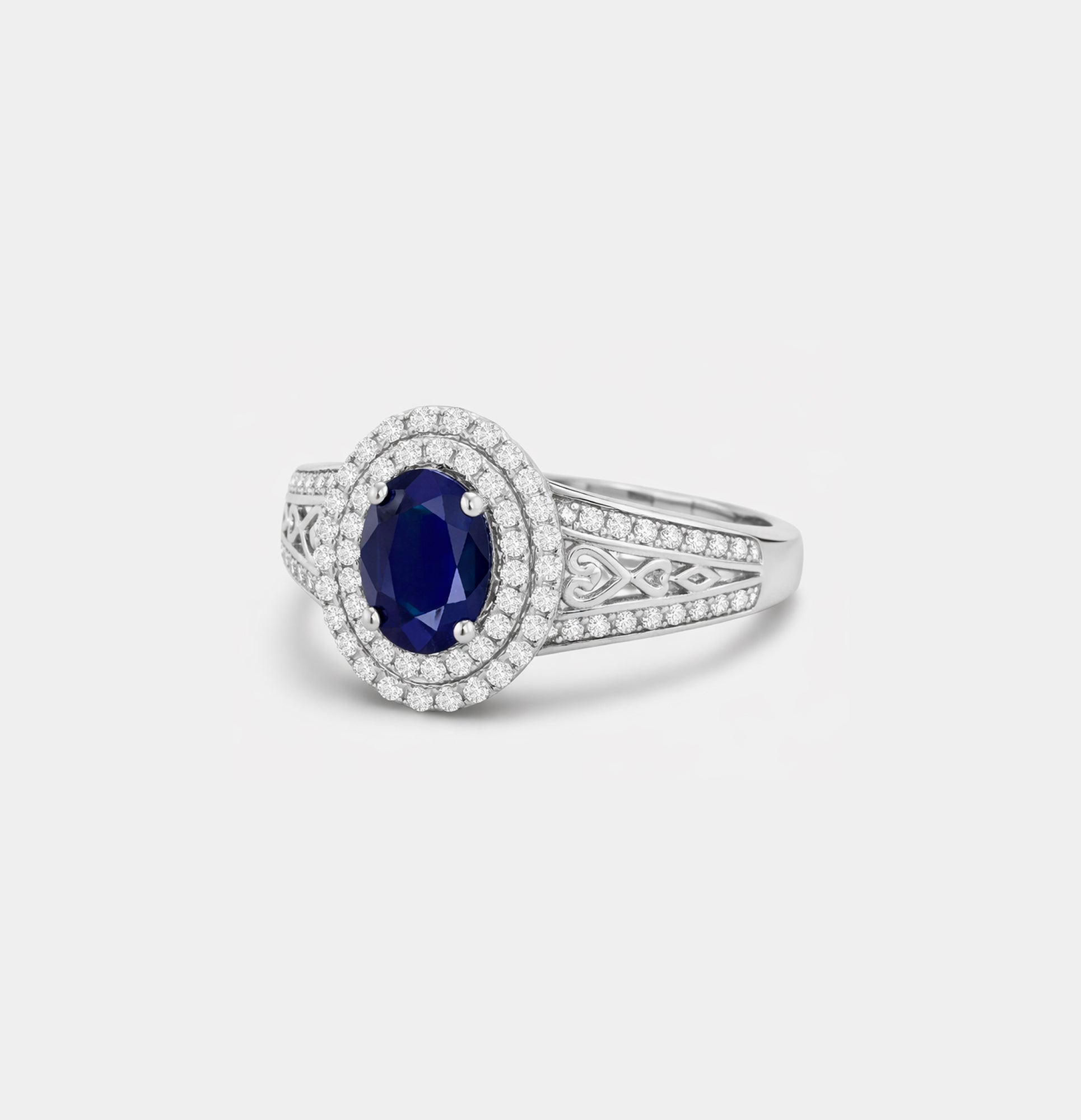 Angled view of an oval blue sapphire double halo ring in 925 sterling silver with sparkling accent stones