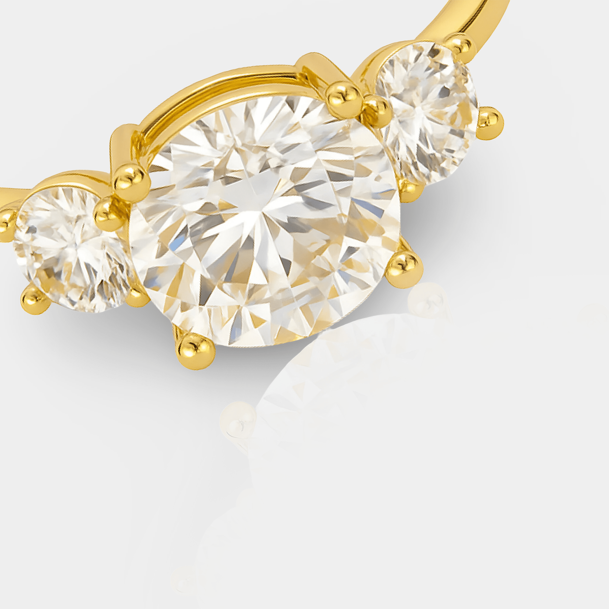 Macro close-up of the three prong-set cubic zirconia stones and polished 14K gold band on the trilogy ring