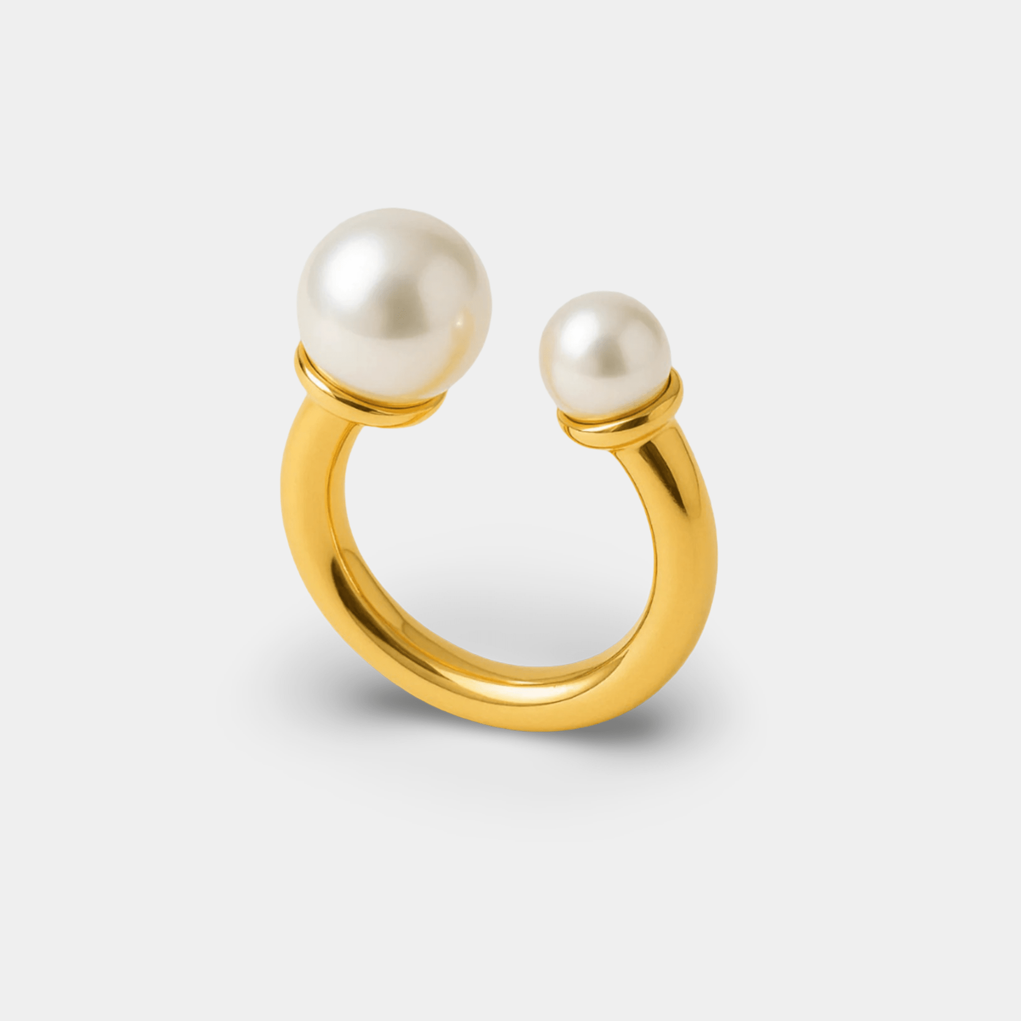 Close-up of the twin pearl arc ring showing the pearl and zircon inlay along the gold arc band