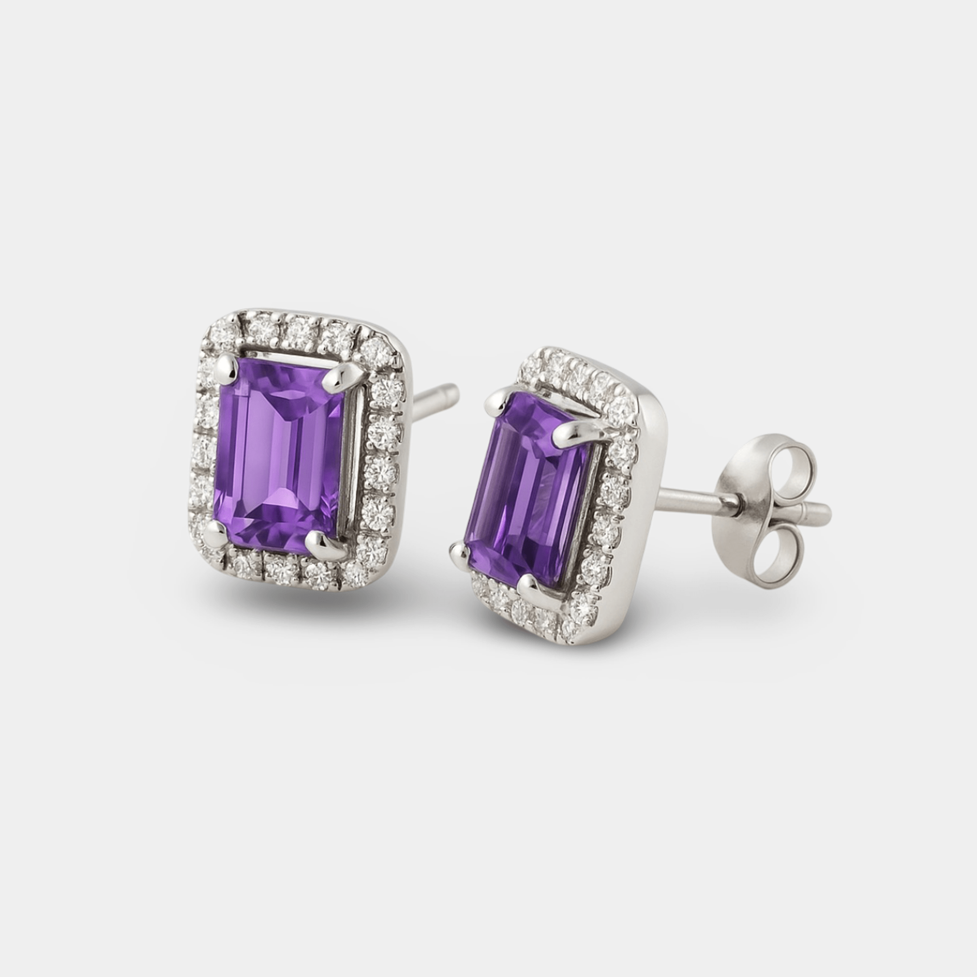Angled view of the amethyst halo studs showing the emerald-cut stones, cubic zirconia halos, and silver posts