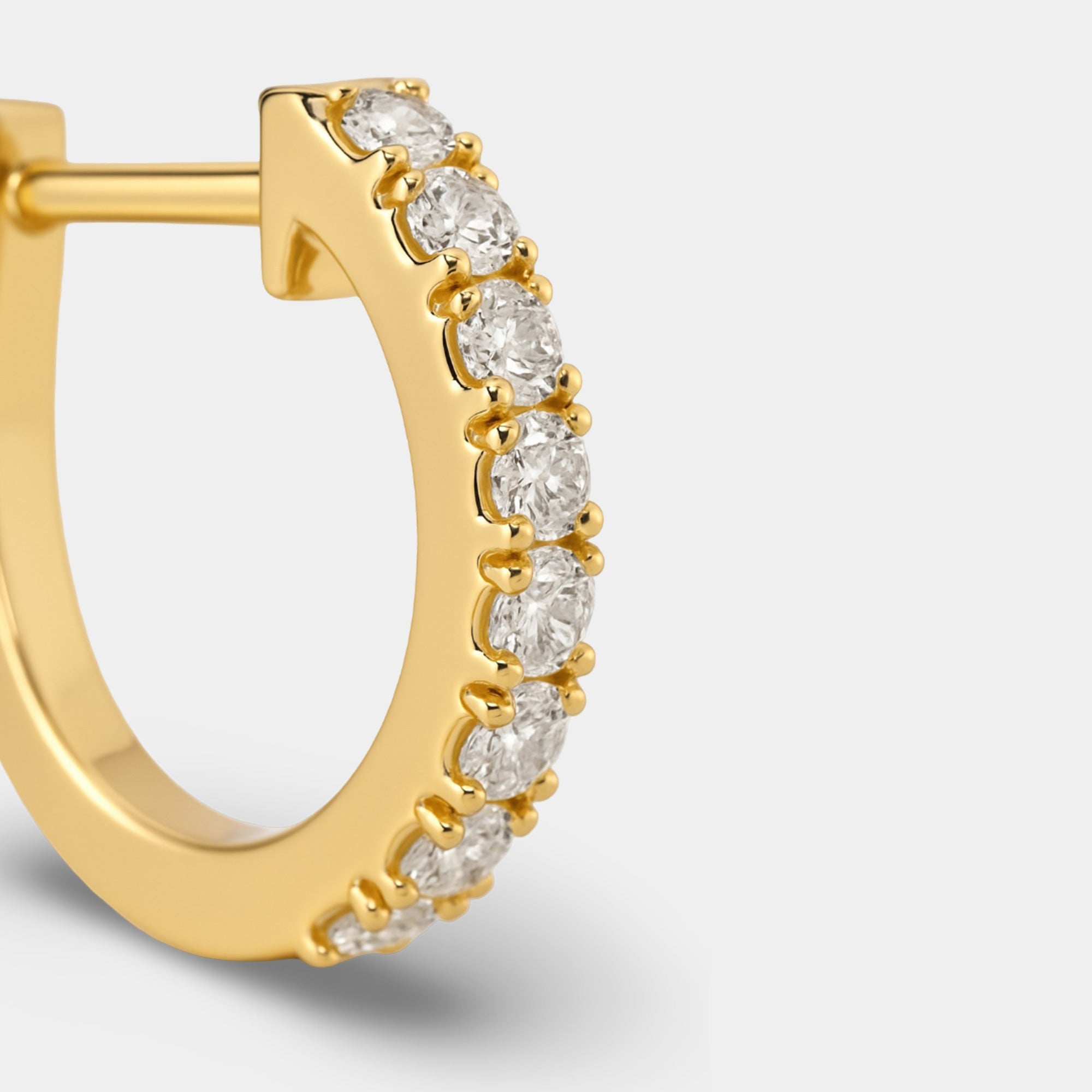 Pair of gold CZ huggie hoop earrings shown from the front on a soft background
