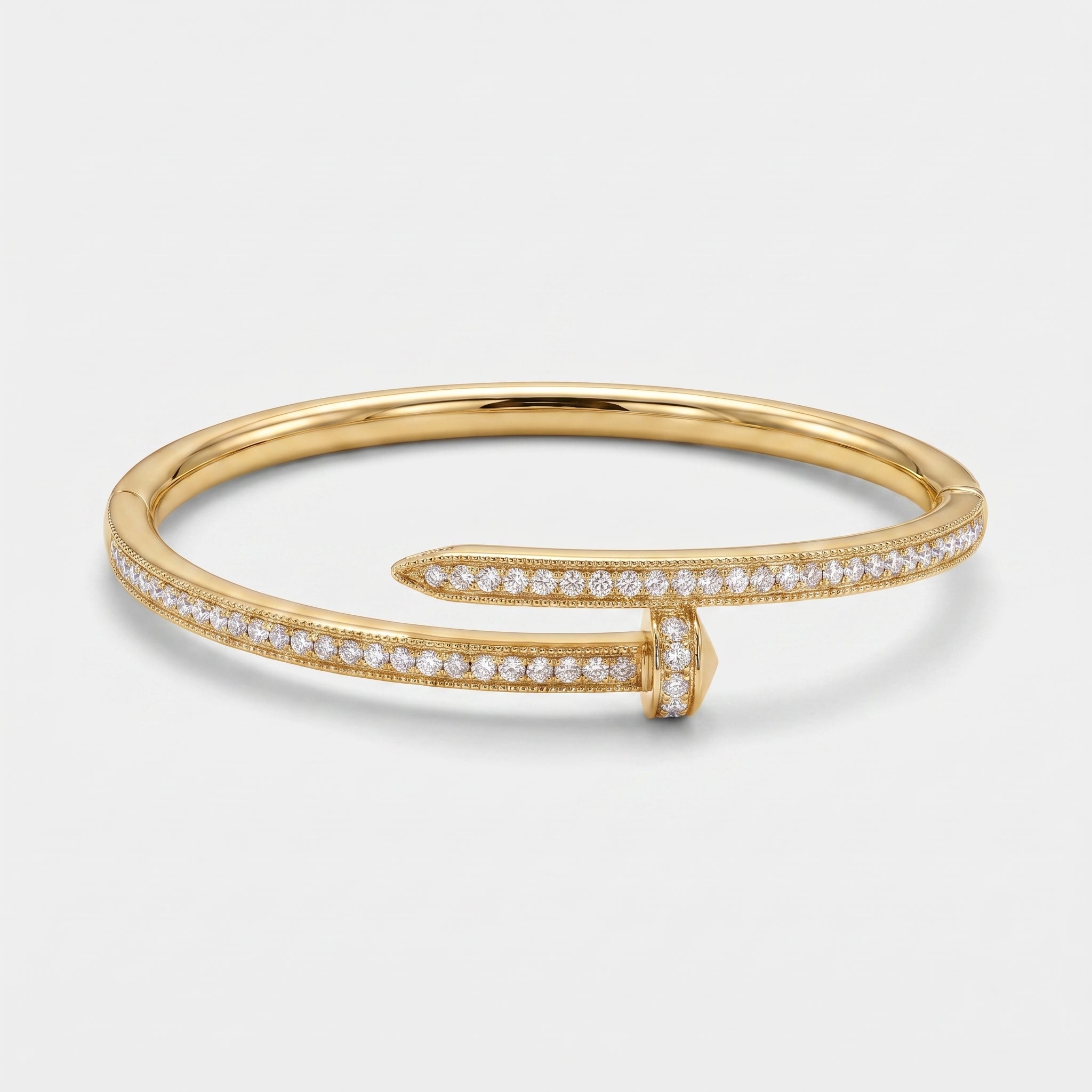 A gold bangle bracelet with pavé-set clear stones along the front and tip, photographed on a clean light gray background.