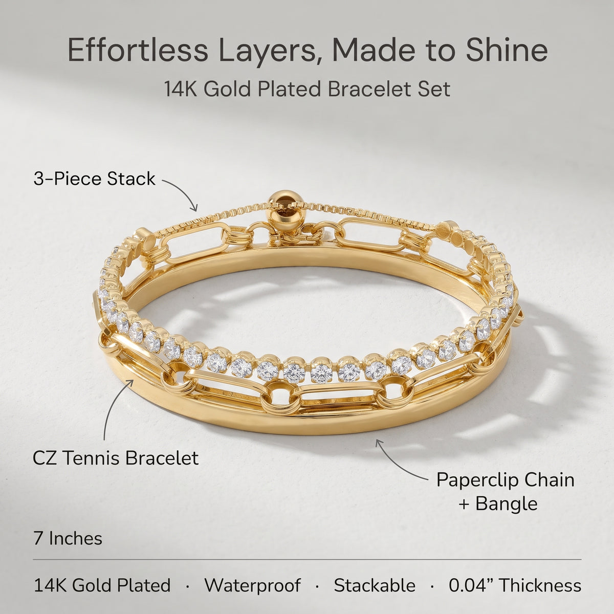 A 14K gold-plated stackable bracelet set shown on a light gray background with callout labels. The set includes a CZ tennis bracelet and a paperclip chain bangle, with text noting 7 inches length, 14K gold plating, waterproof and stackable features, and 0.