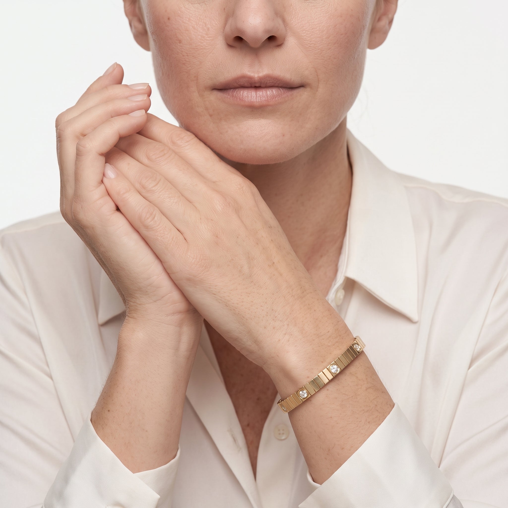 Woman with hands clasped wearing the hinged 14K gold plated bangle bracelet with a white button-down shirt
