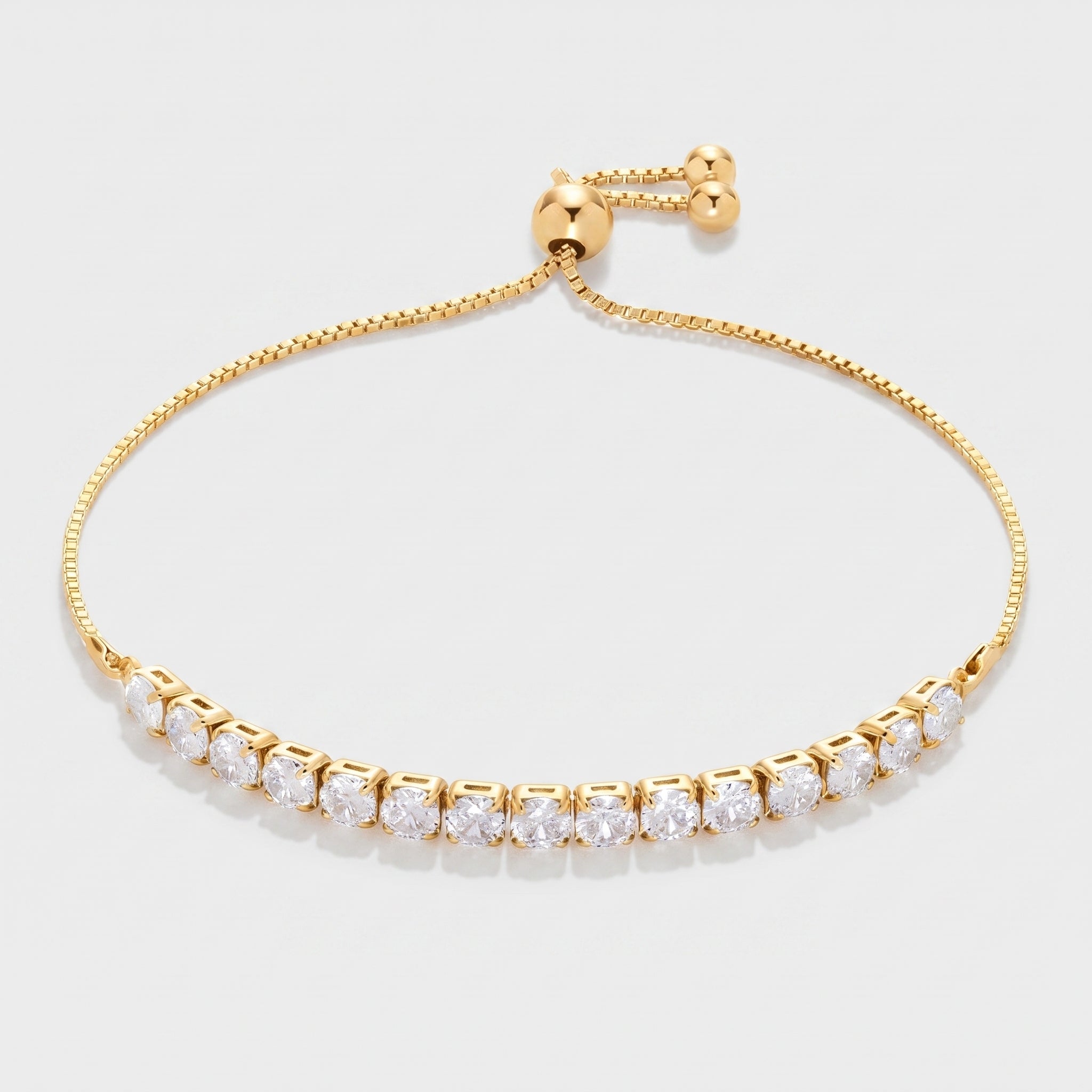 Adjustable 14K gold plated cubic zirconia tennis bracelet with a bolo slider clasp on a white background