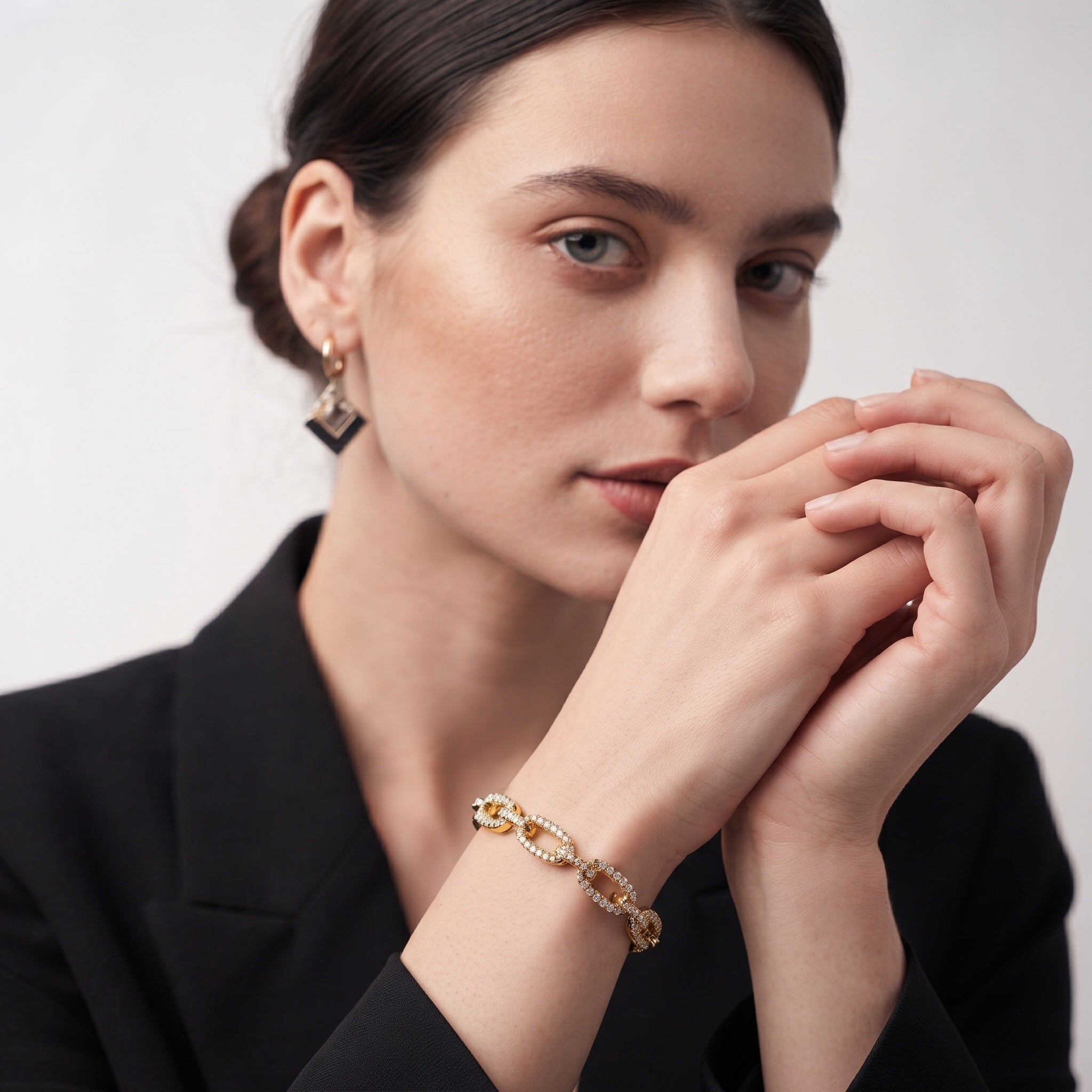 Model wearing a 14K gold plated CZ pave chain link cuff bracelet and gold earrings