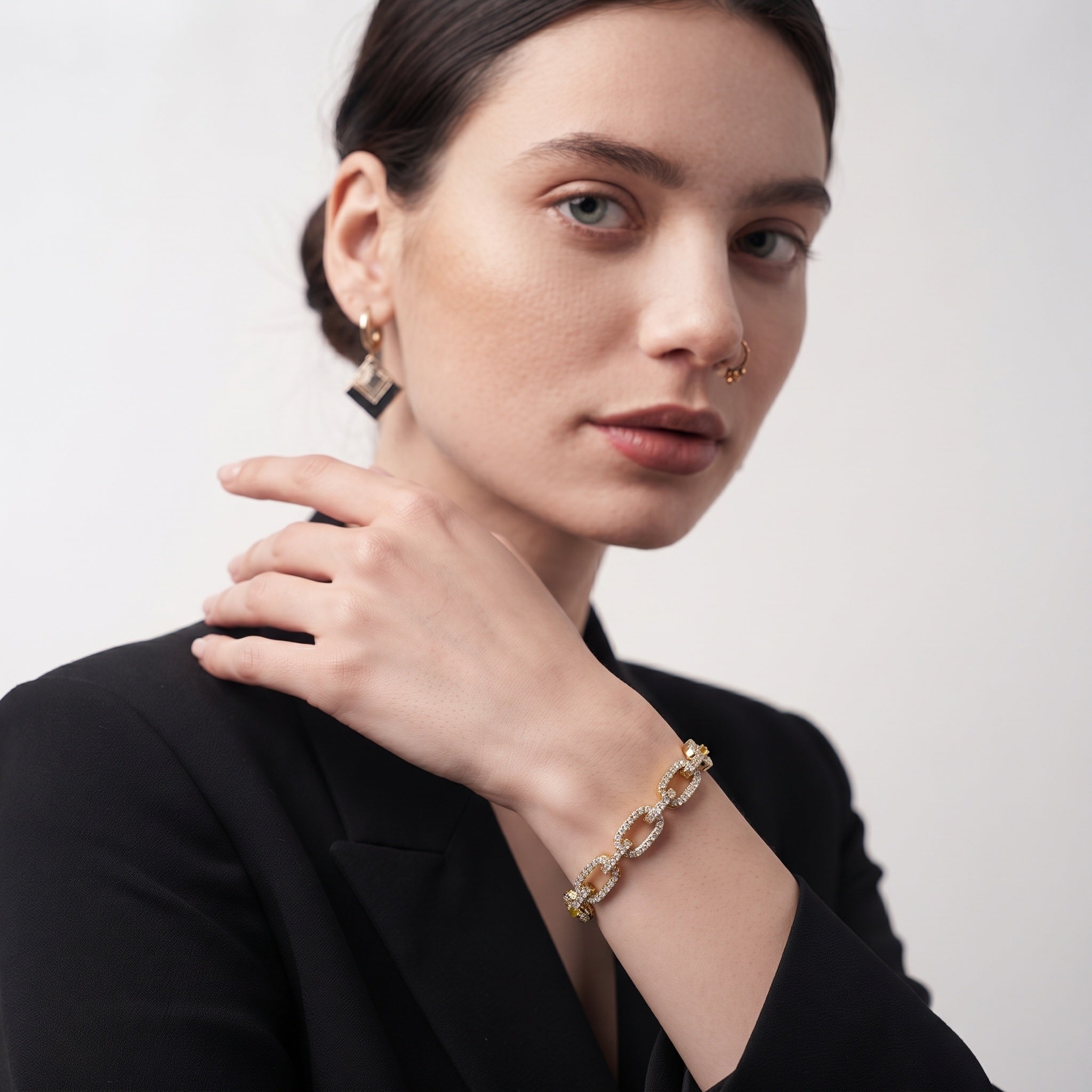 Adjustable open cuff bracelet with gold oval links worn on a woman's wrist