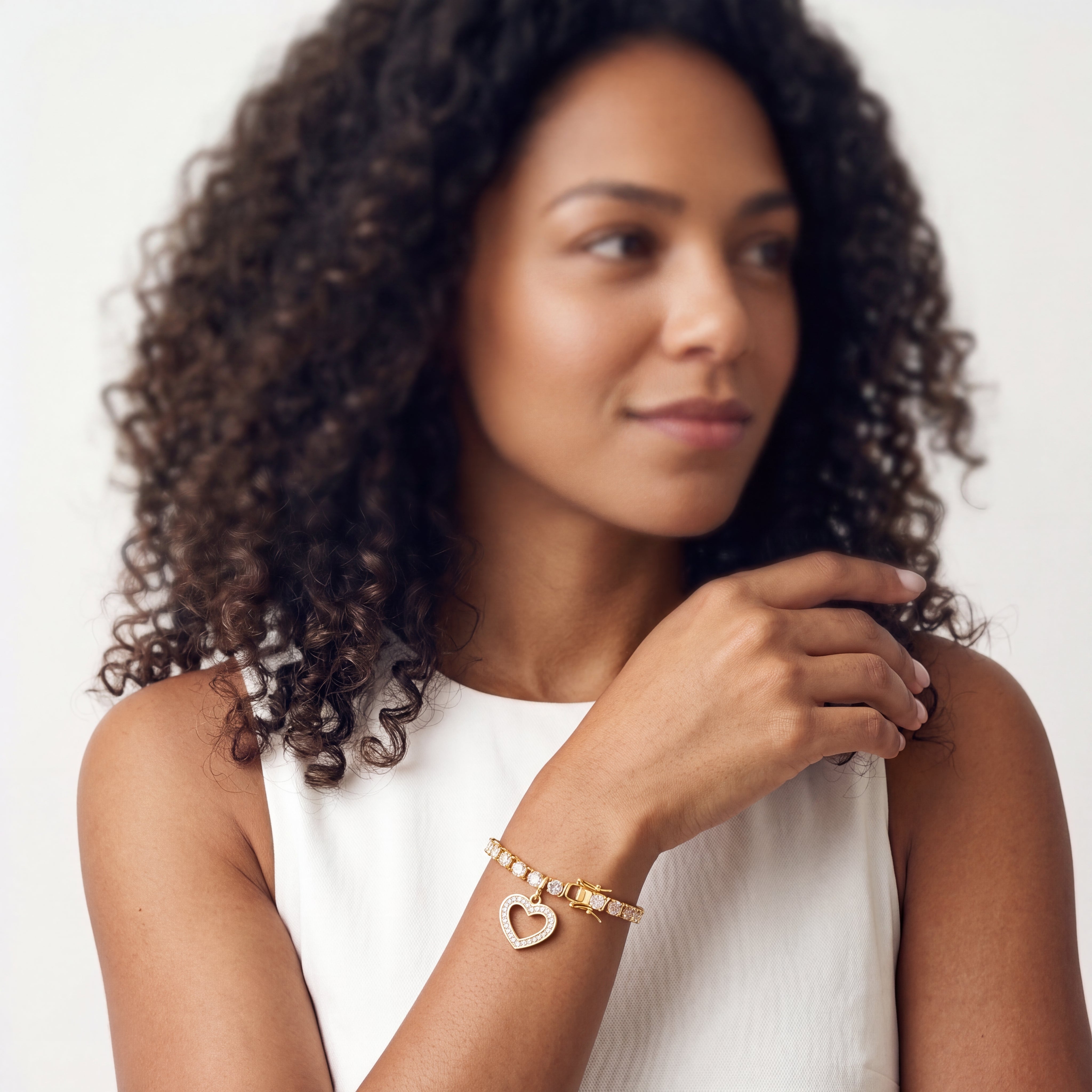 Open heart charm set with diamond accents on a gold tennis bracelet