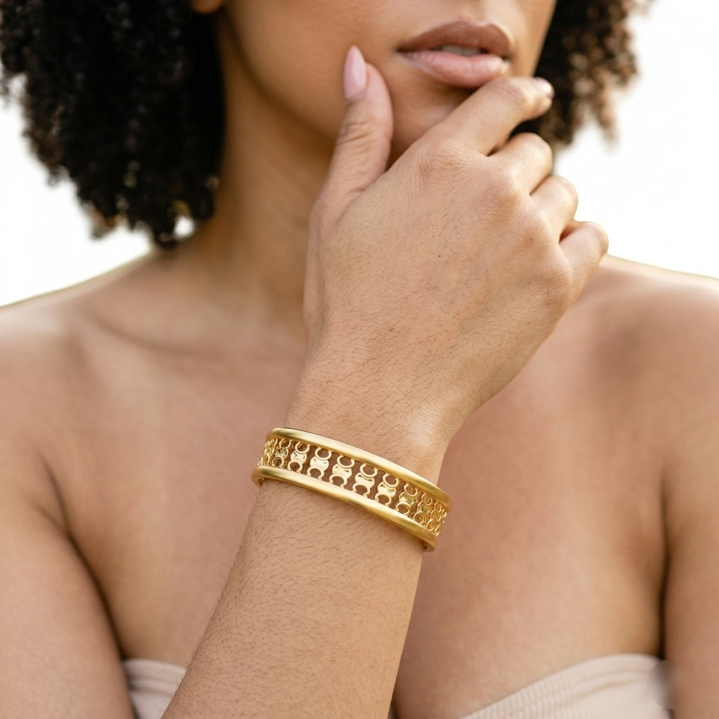 Woman wearing a wide gold openwork cuff bracelet on her wrist