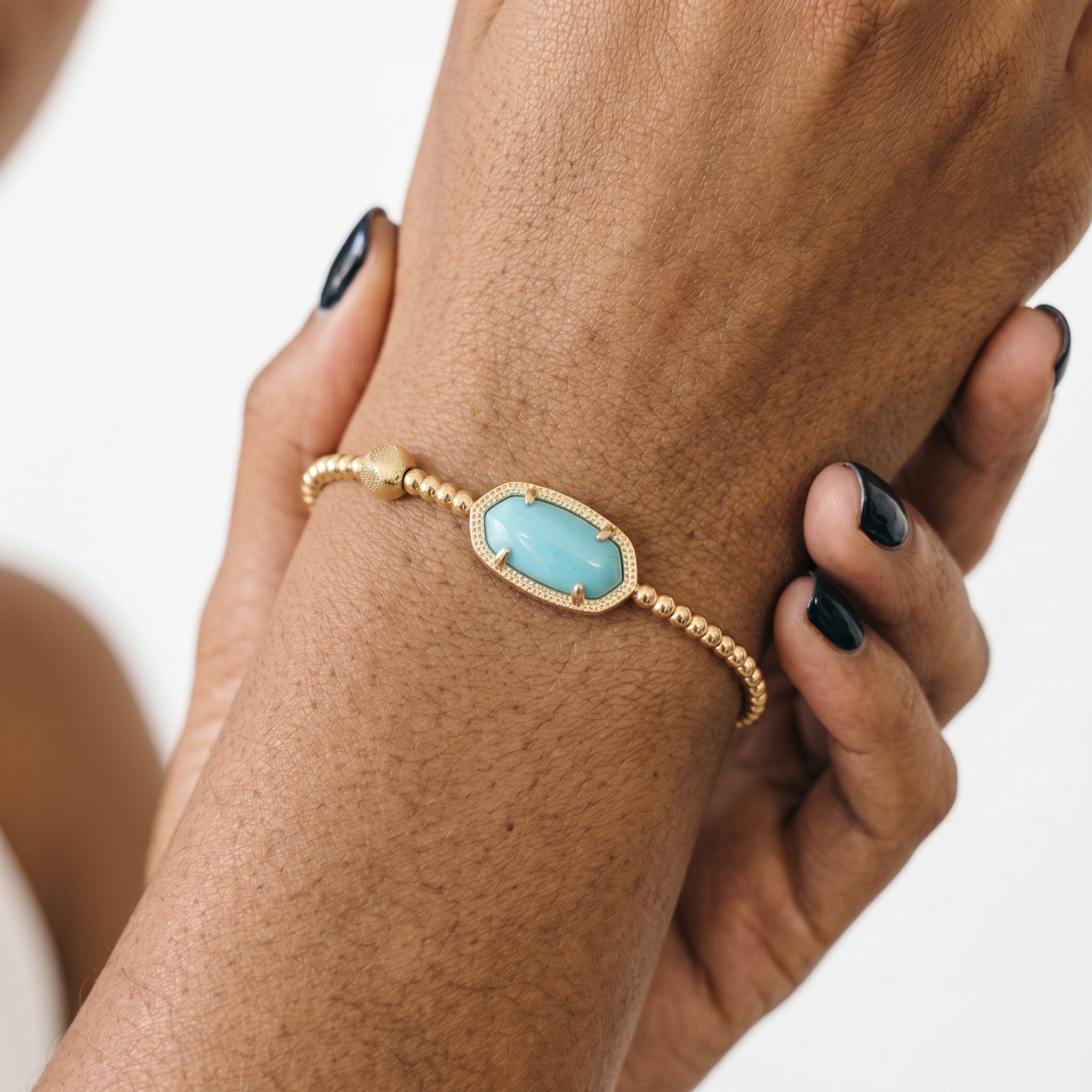 Woman wearing a turquoise magnesite gold stretch bracelet on her wrist