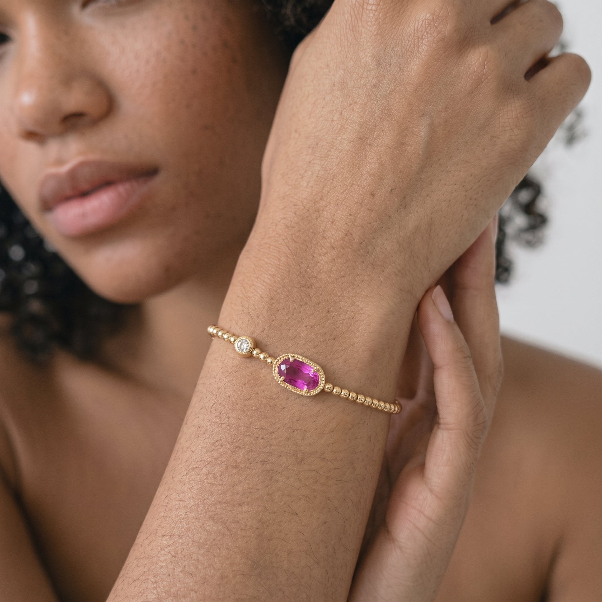 Gold beaded stretch bracelet with an oval pink crystal shown flat