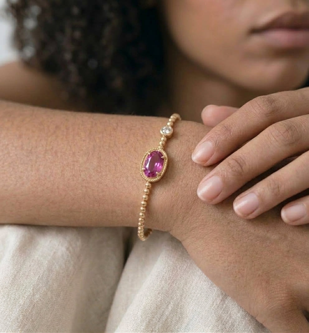 Close view of the oval pink crystal and gold bead band on a wrist
