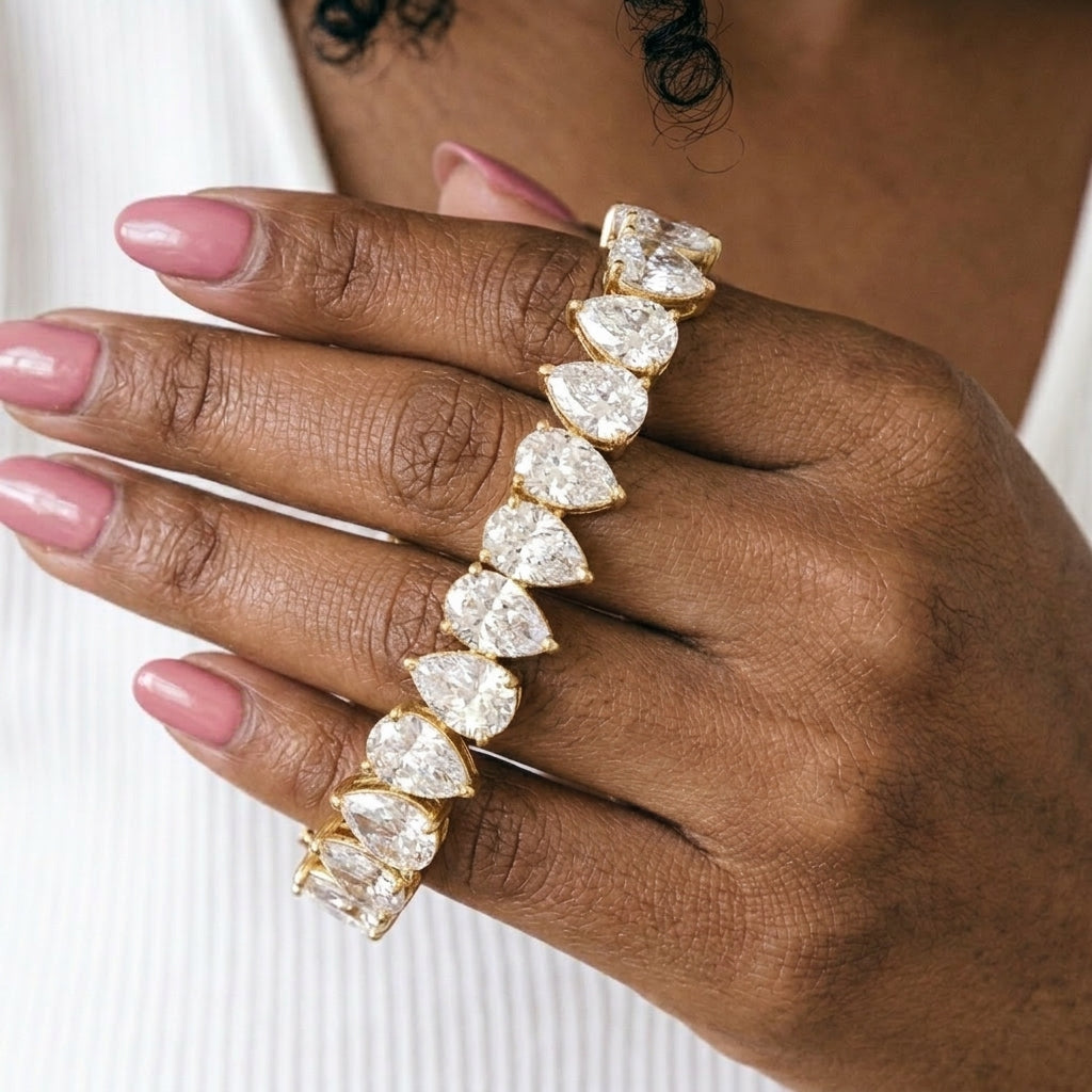Pear cut cubic zirconia tennis bracelet draped over fingers showing sparkle detail