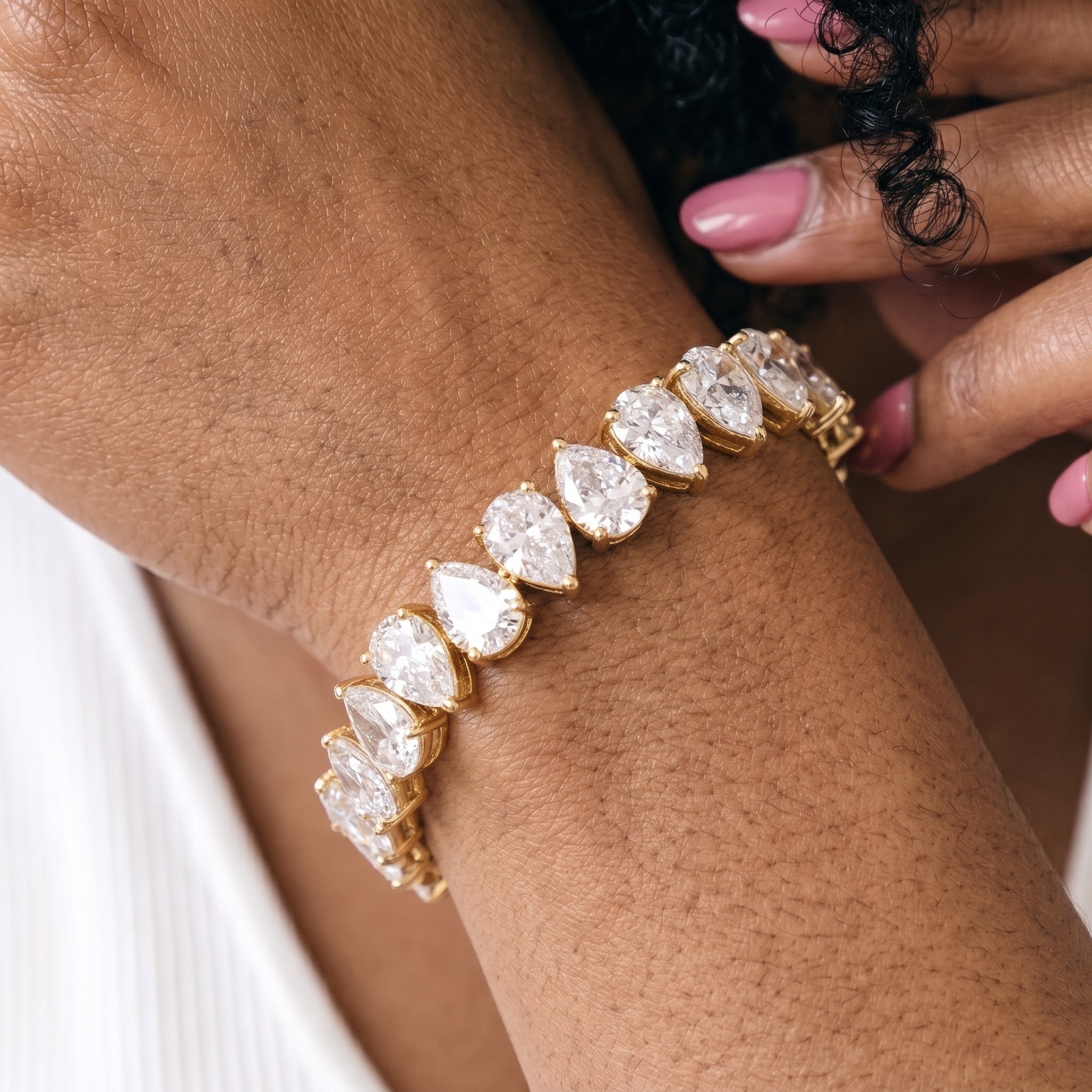 Woman wearing 14K gold plated pear CZ tennis bracelet on her wrist