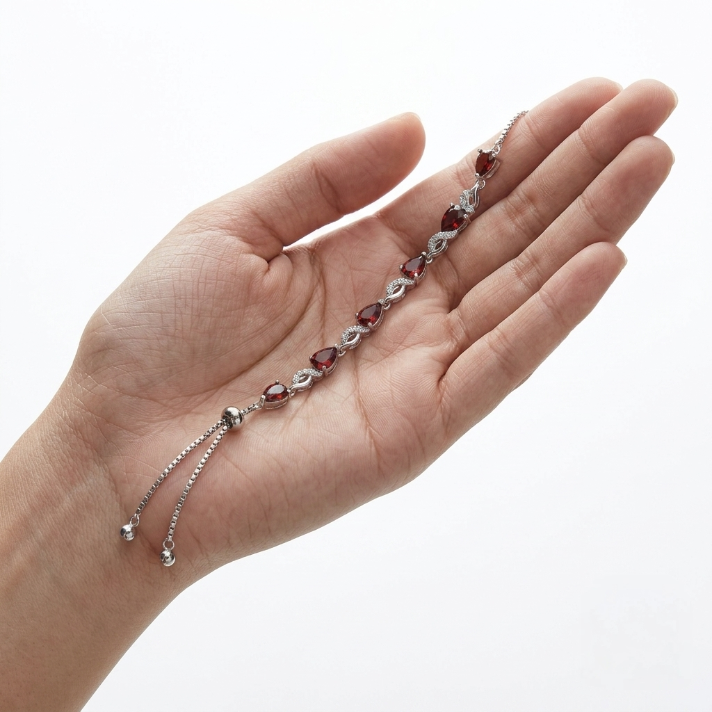 Garnet teardrop tennis bracelet with adjustable slide clasp laid in an open hand