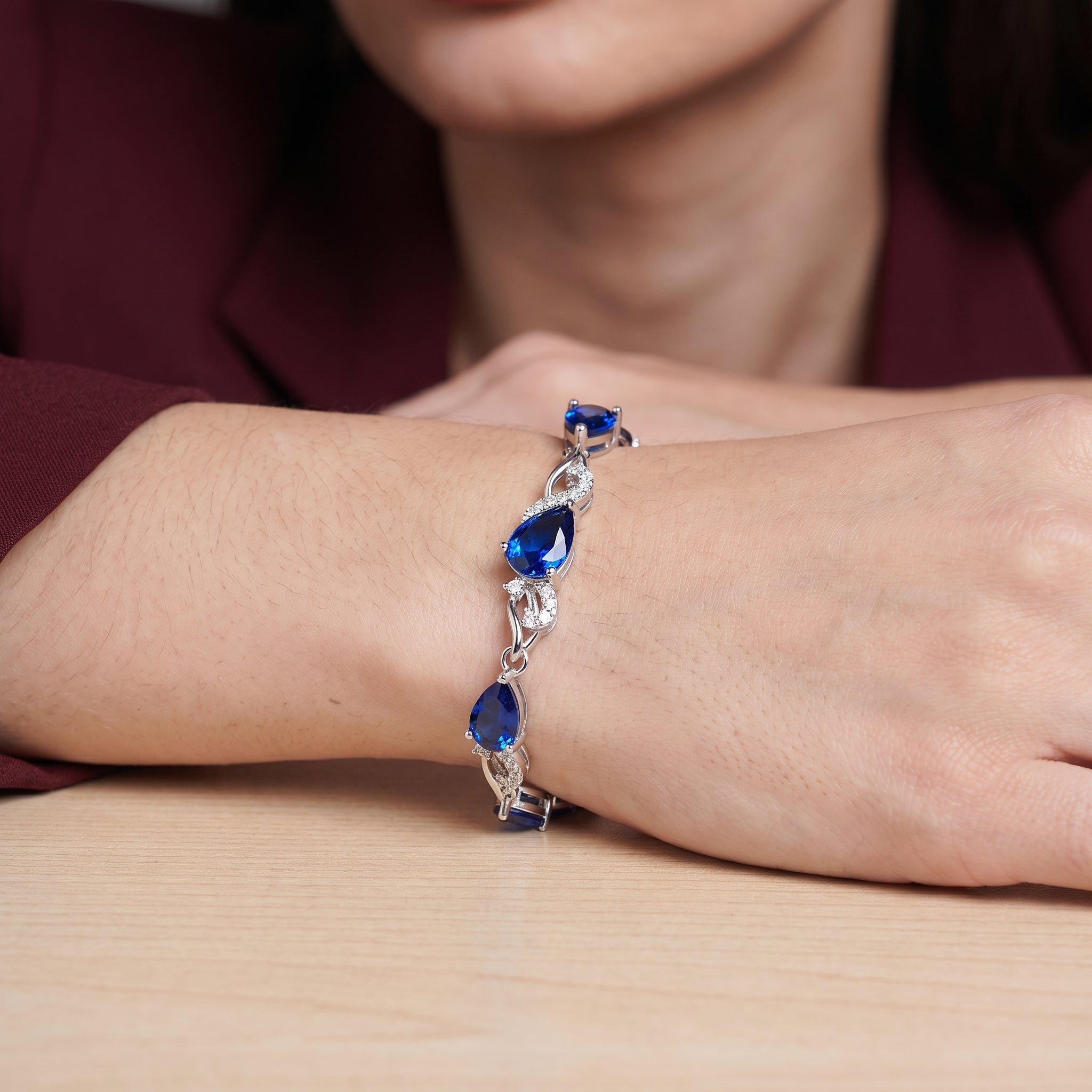 Close-up of sapphire tennis bracelet on wrist with blurred background