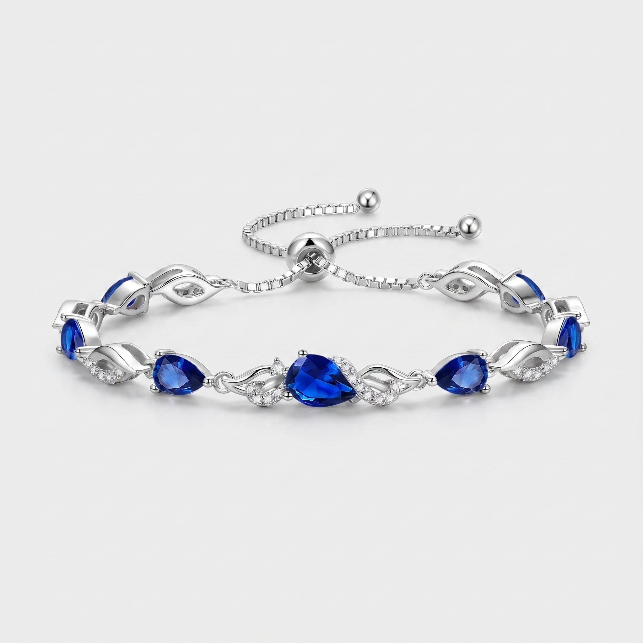 Sterling silver sapphire teardrop tennis bracelet with adjustable bolo chain on white background