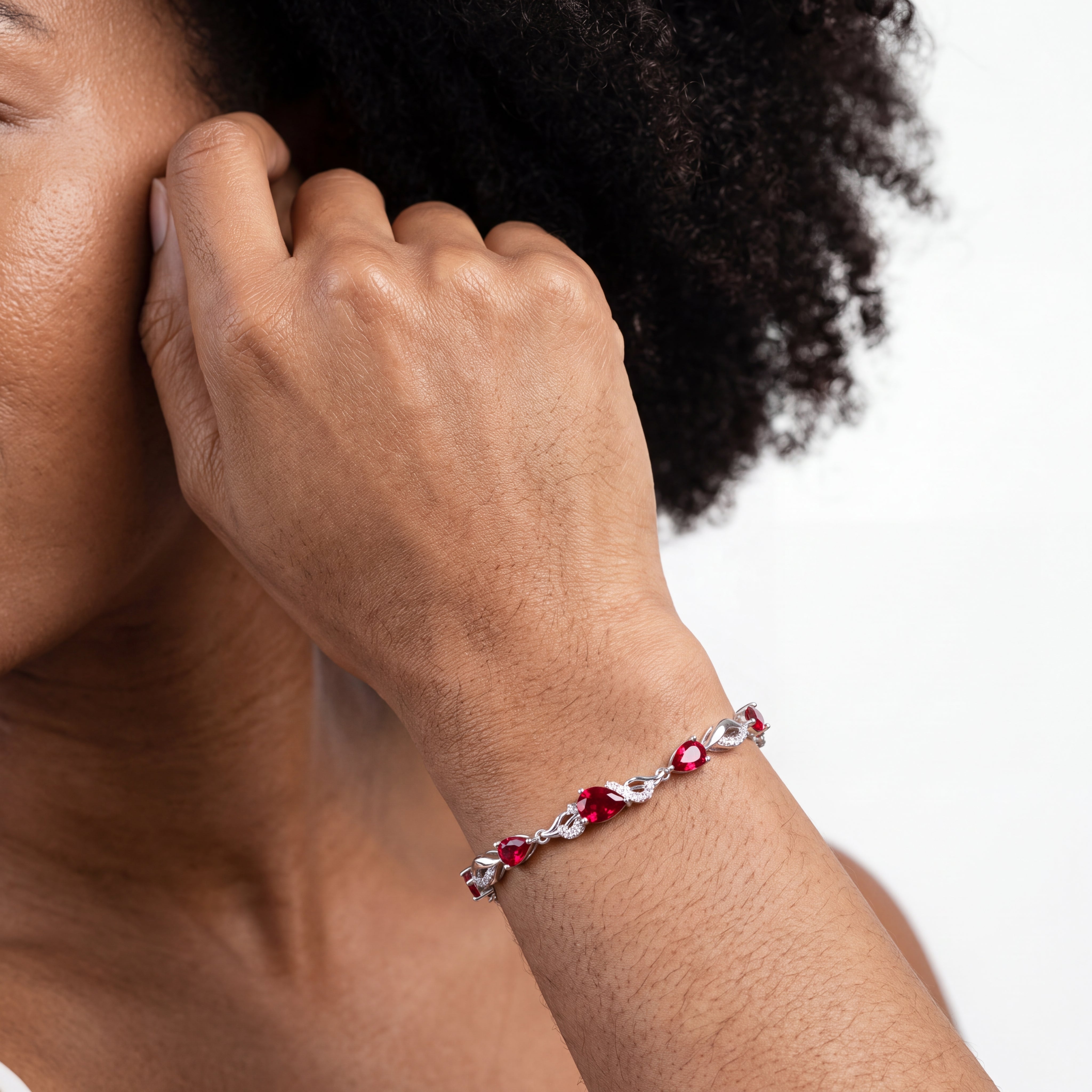 Woman wearing the ruby bracelet on her wrist with her hand near her hair.