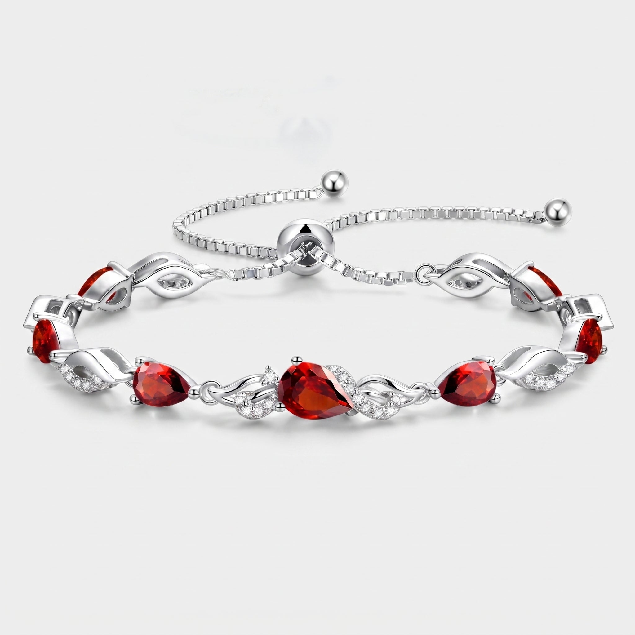 Ruby teardrop tennis bracelet in sterling silver laid flat, showing the adjustable bolo clasp and leaf-link design.